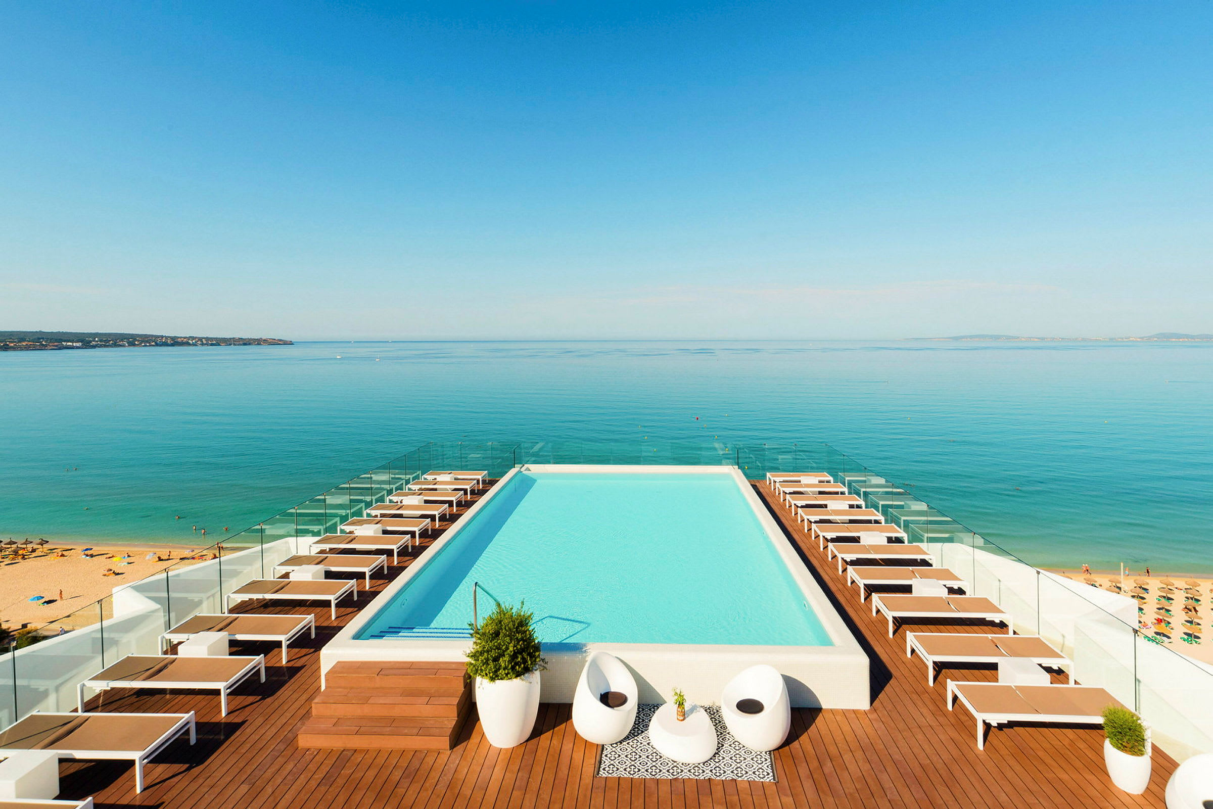 En infinitypool med solstolar och utsikt över havet. (AI-genererad text)