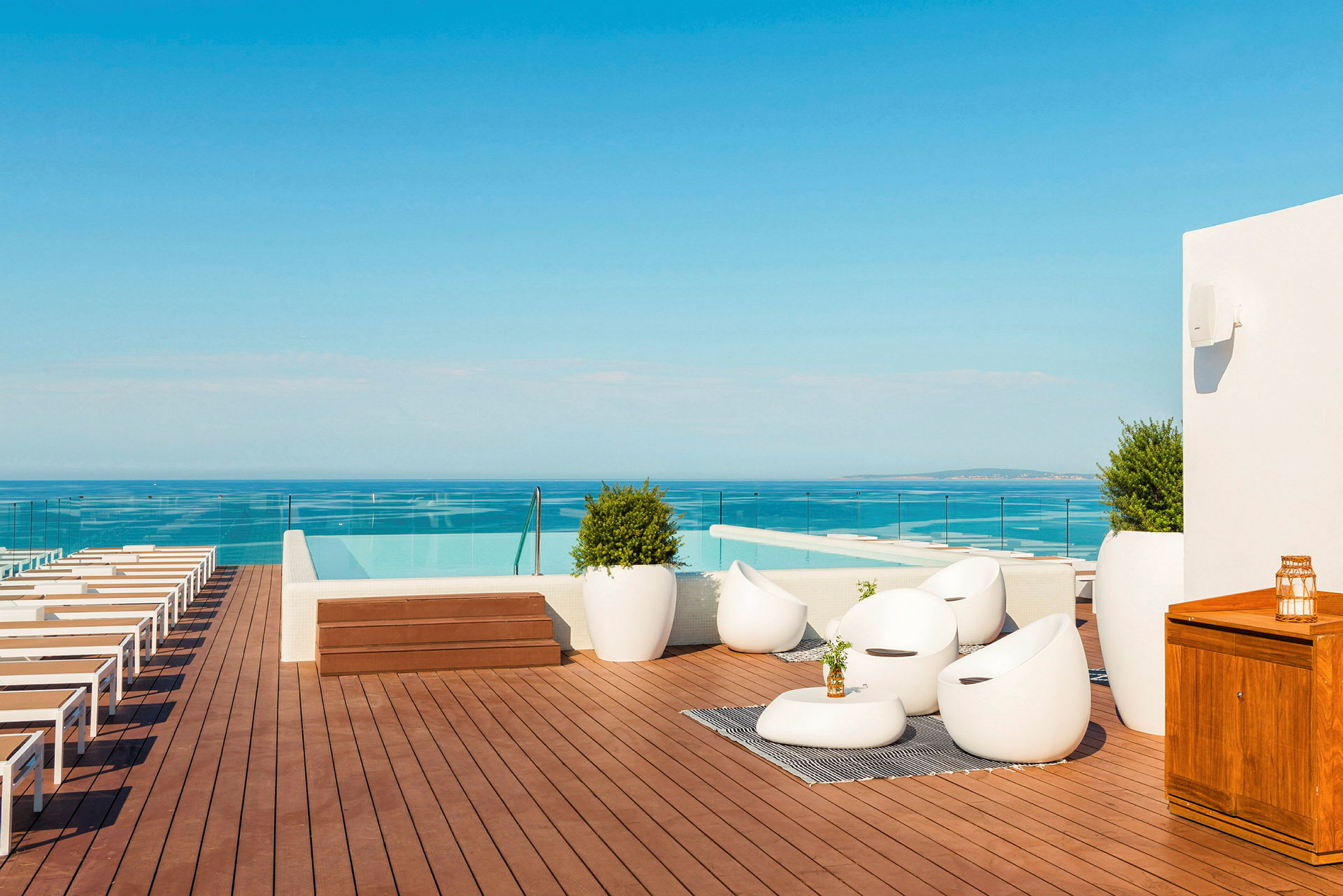 En takterrass med solstolar, sittgrupp och infinitypool med utsikt över havet. (AI-genererad text)