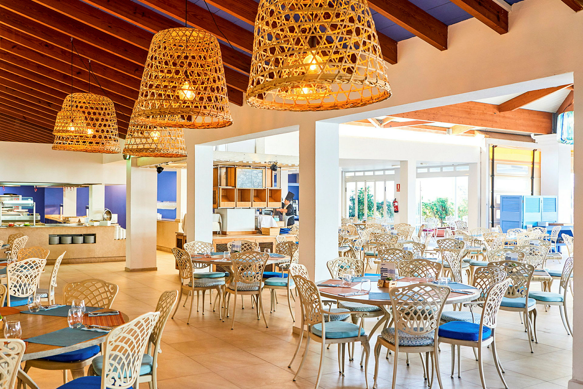 Ljus och luftig restaurang med elegant möblemang och stora korglampor. (AI-genererad text)