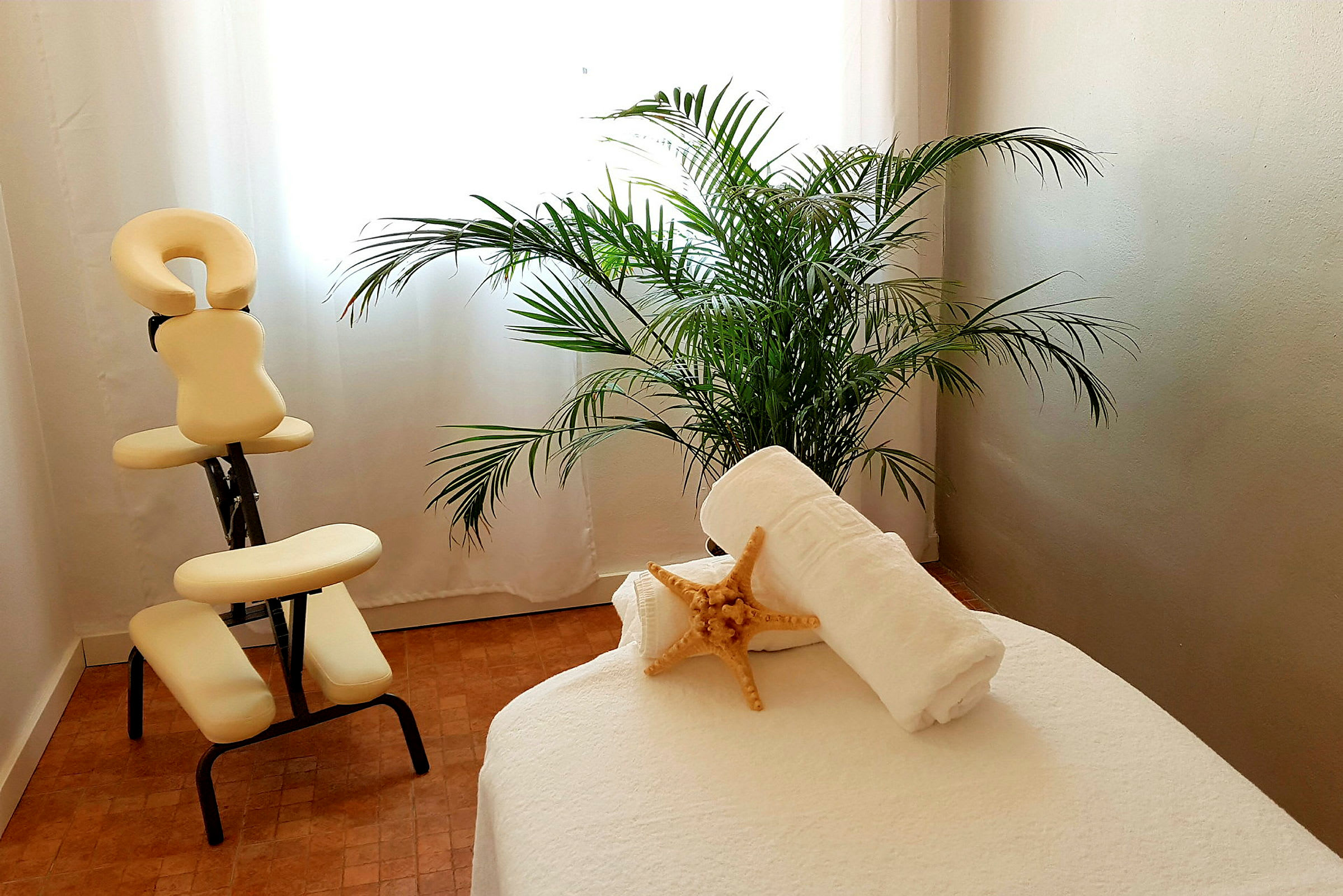 Ett rum med massageutrustning, en grön växt och hopvikta handdukar. (AI-genererad text)