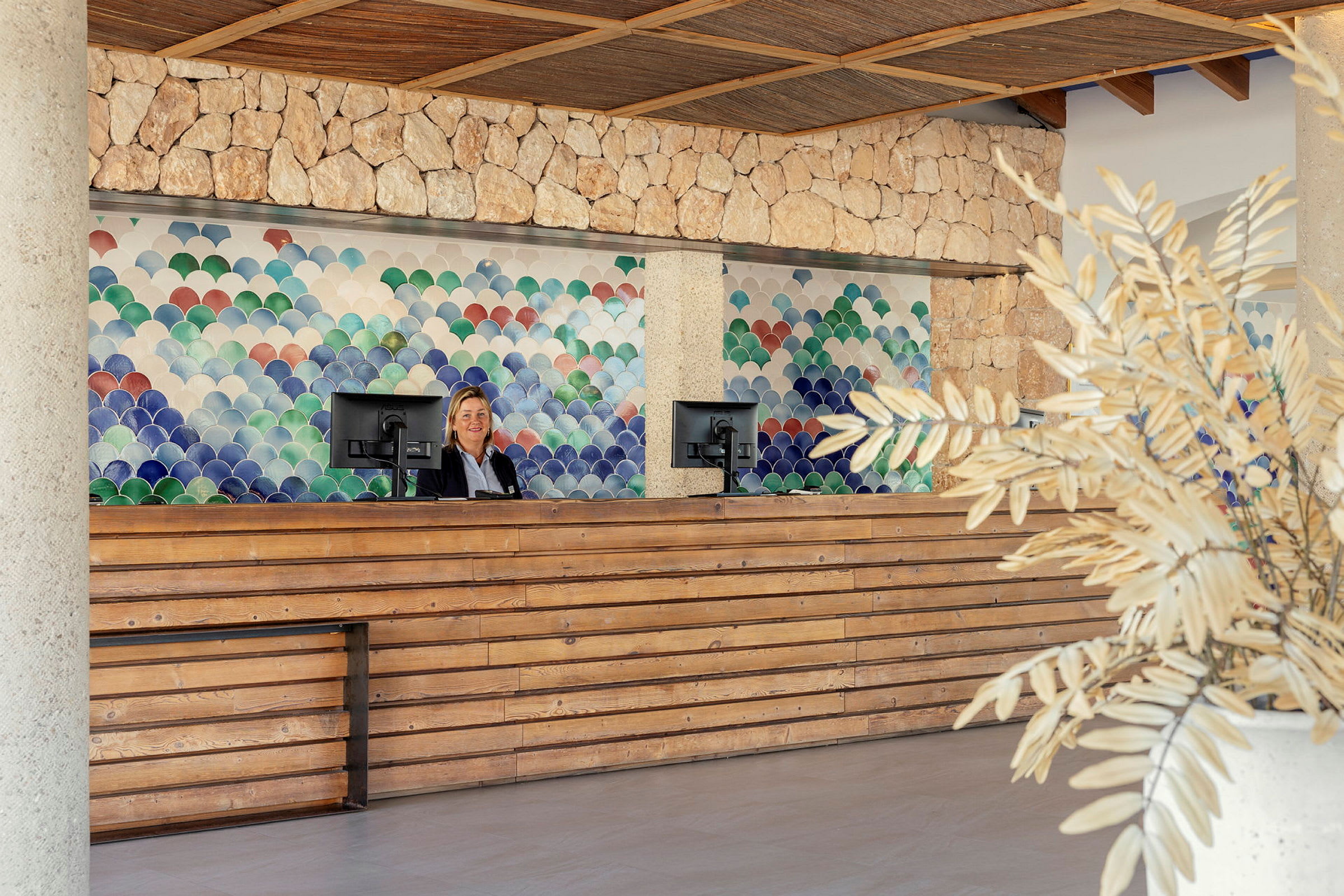 Reception med en trädisk, en person bakom disken och färgglada väggpaneler i bakgrunden. (AI-genererad text)