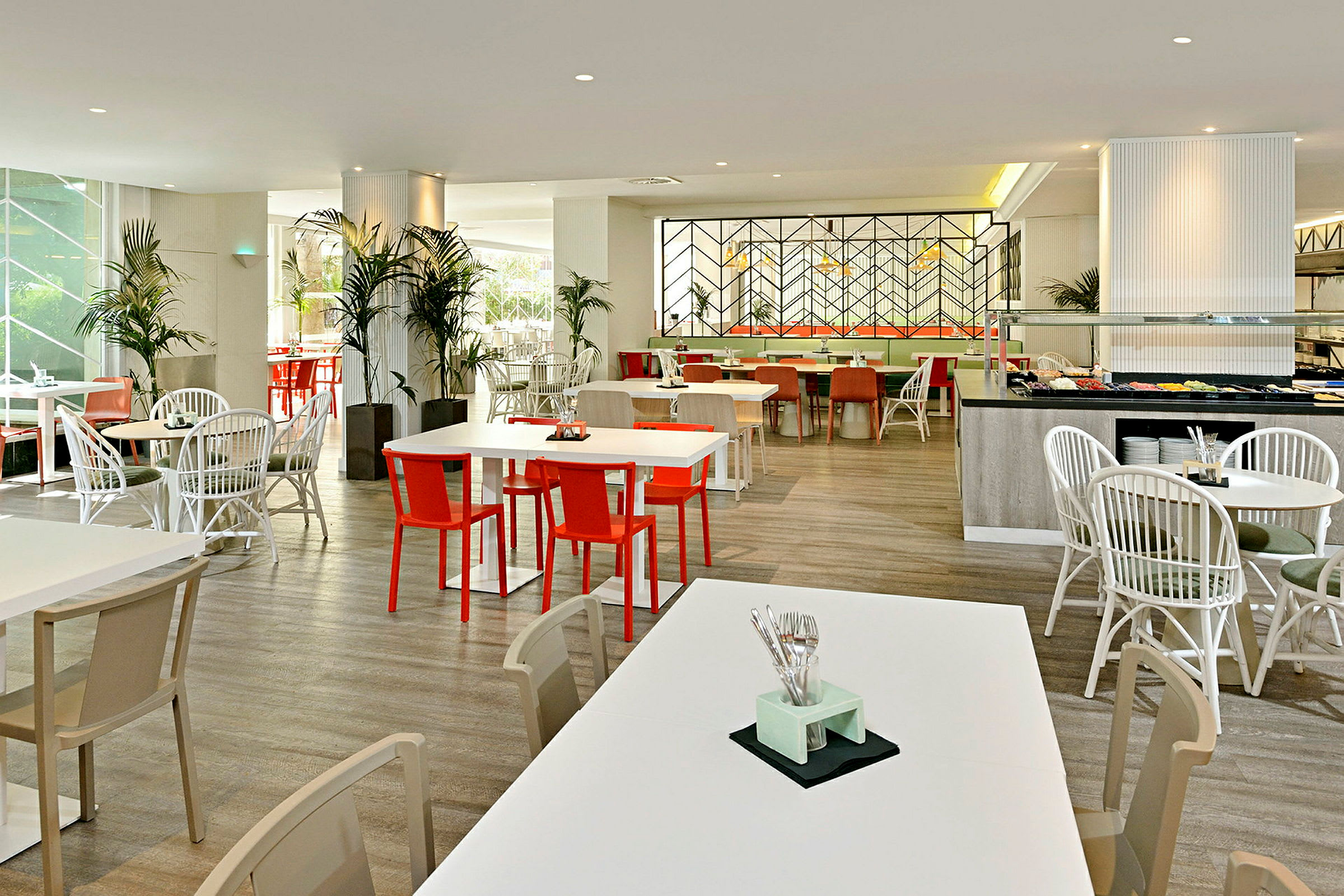 En ljus och modern restaurang med vita bord och färgglada stolar. (AI-genererad text)
