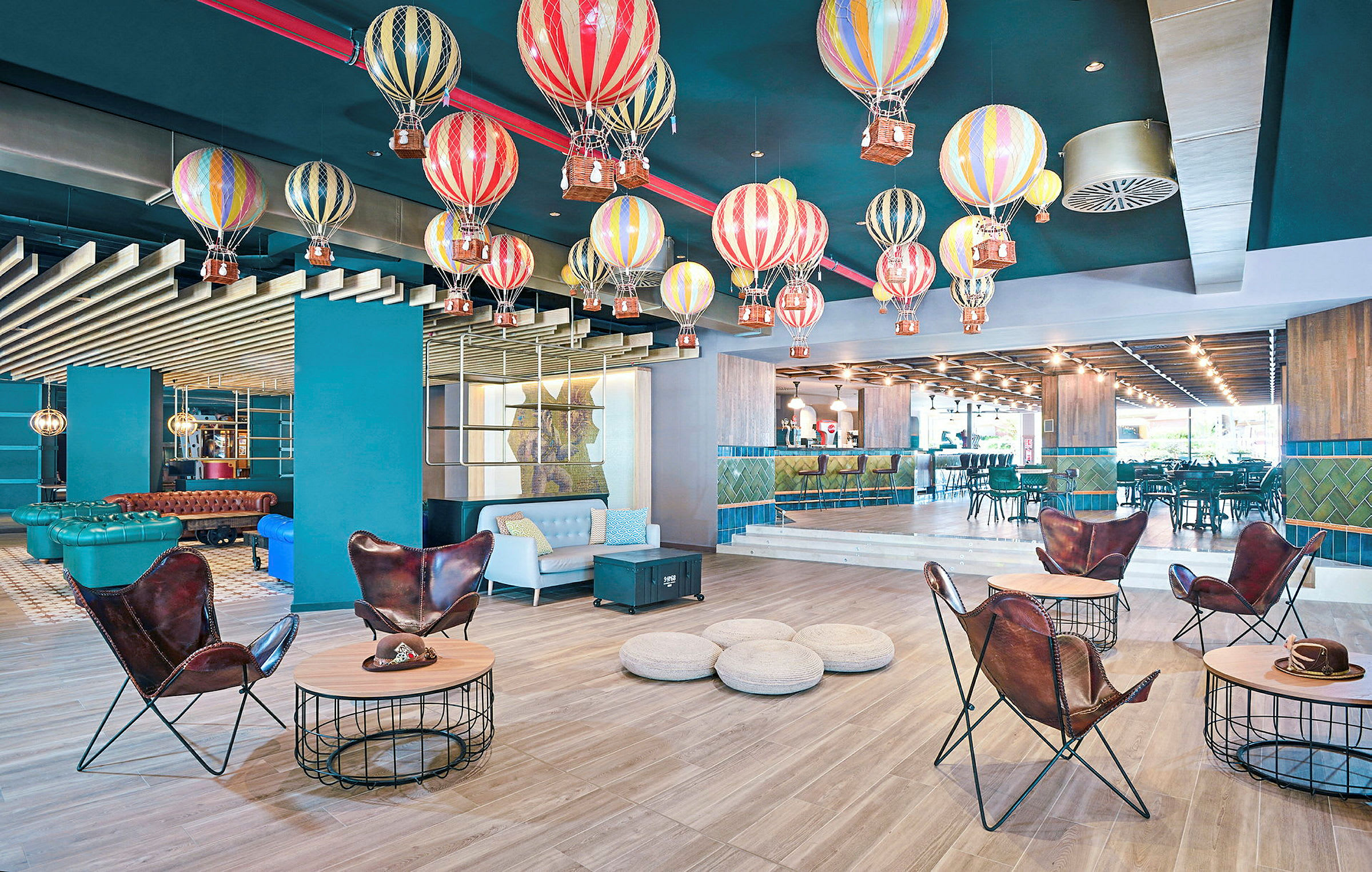 Ett rum med färgglada luftballonger hängande från taket som dekor, moderna möbler och en bar i bakgrunden. (AI-genererad text)