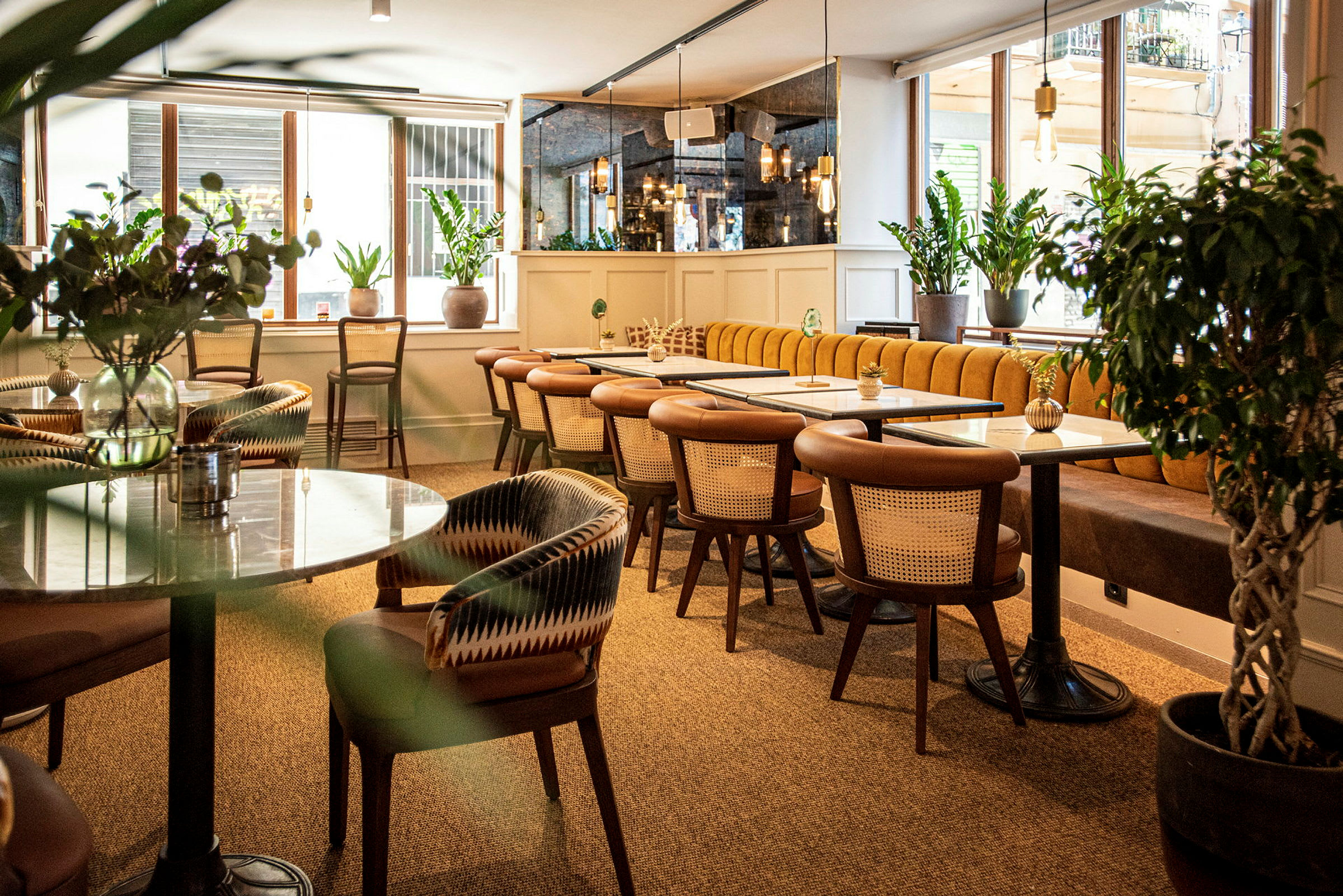 Ett modernt kafé med trästolar och marmorbord, omgivna av gröna växter. (AI-genererad text)
