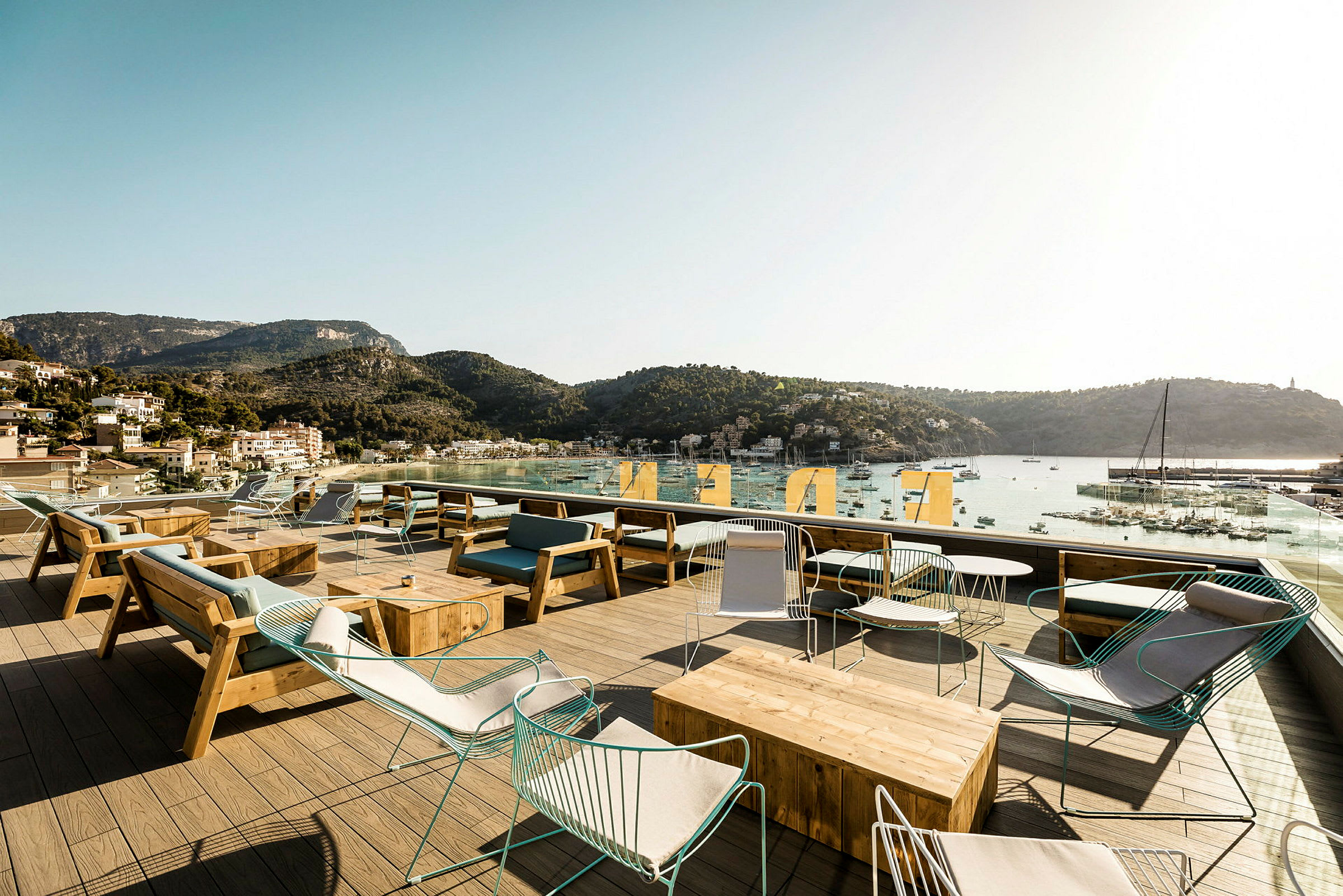Uteservering med utsikt över en hamn och berg i bakgrunden. (AI-genererad text)