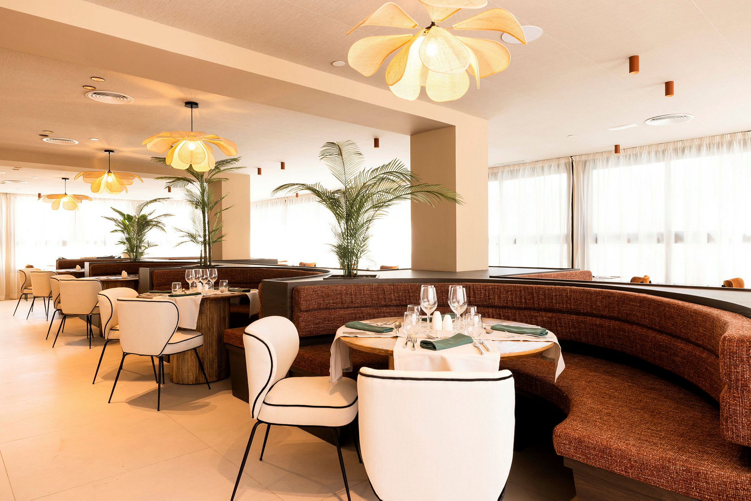 Restaurang med elegant inredning, bestående av runda bord med dukar och vinglas samt bekväma stolar och soffor. (AI-genererad text)