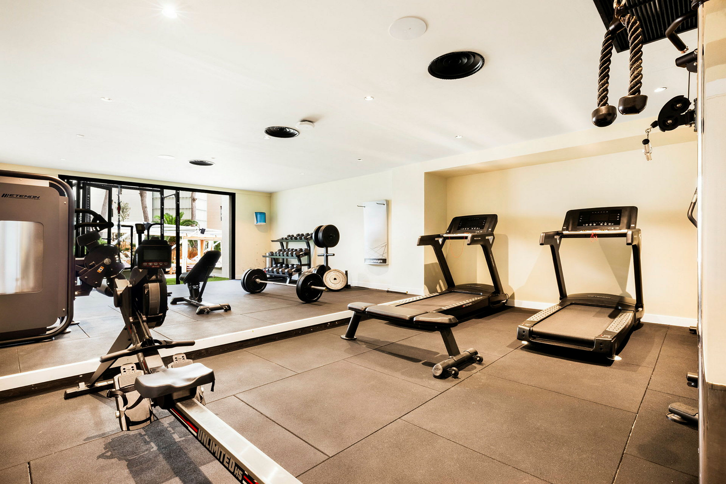 Ett gym med olika träningsutrustningar såsom löpband, hantlar och roddmaskin. (AI-genererad text)