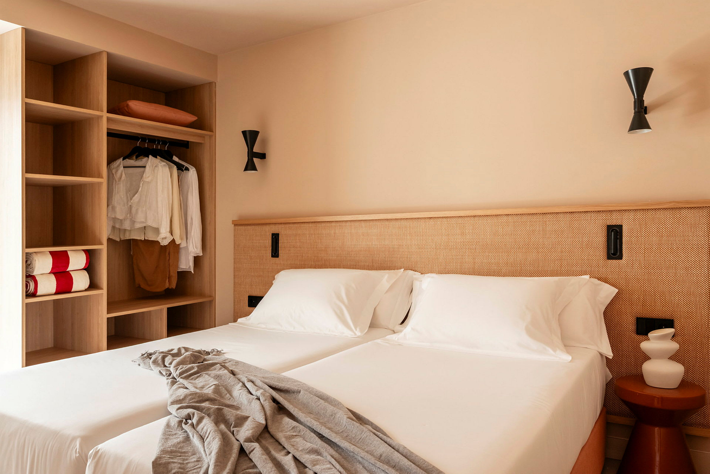 Ett hotellrum med två bäddar, vita sängkläder och en garderob till vänster. (AI-genererad text)