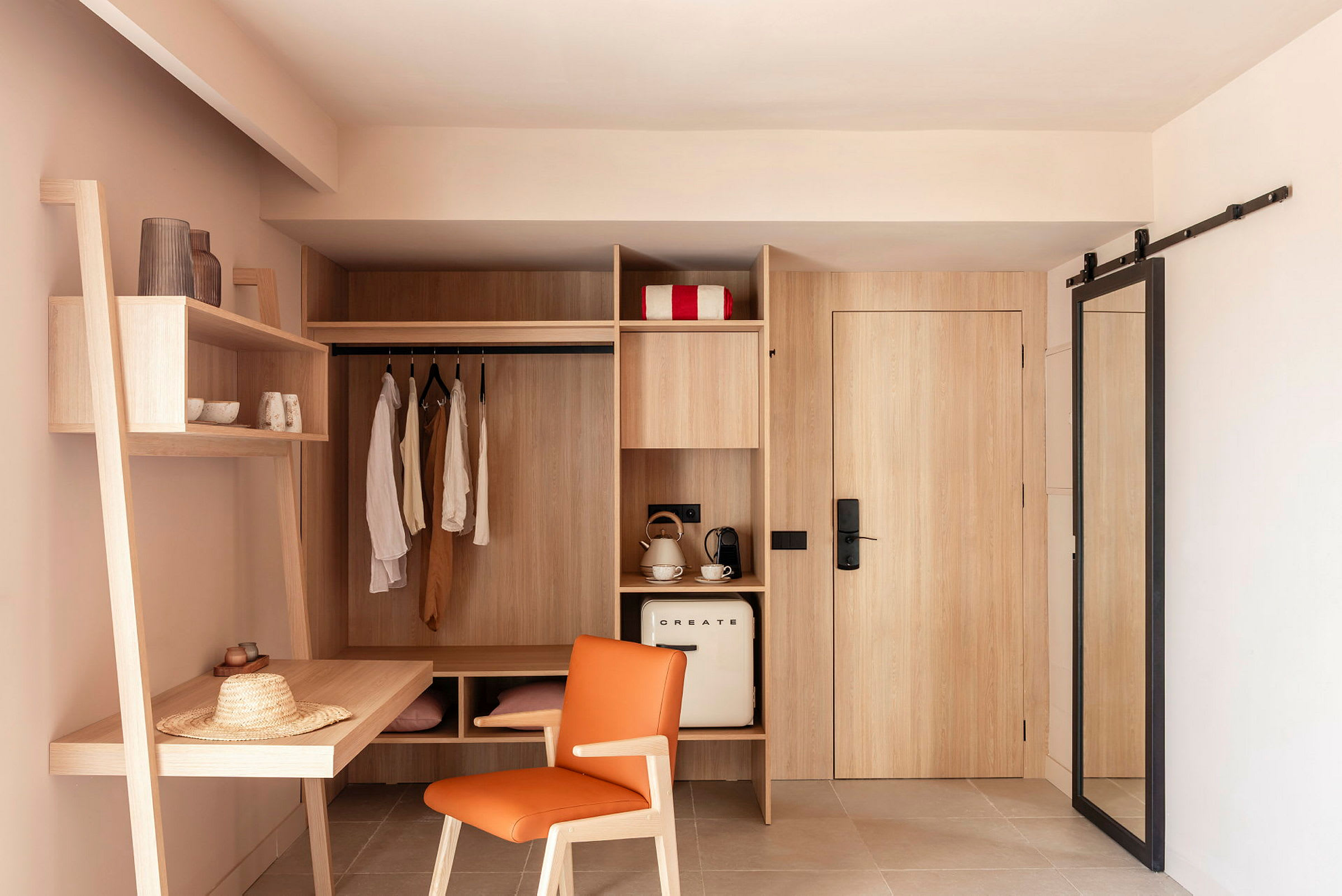 Bilden visar ett hotellrum med en inbyggd förvaringsyta, inklusive krokar, hyllor, och ett skrivbord. Ett kylskåp, en kaffemaskin och en vattenkokare syns också. (AI-genererad text)