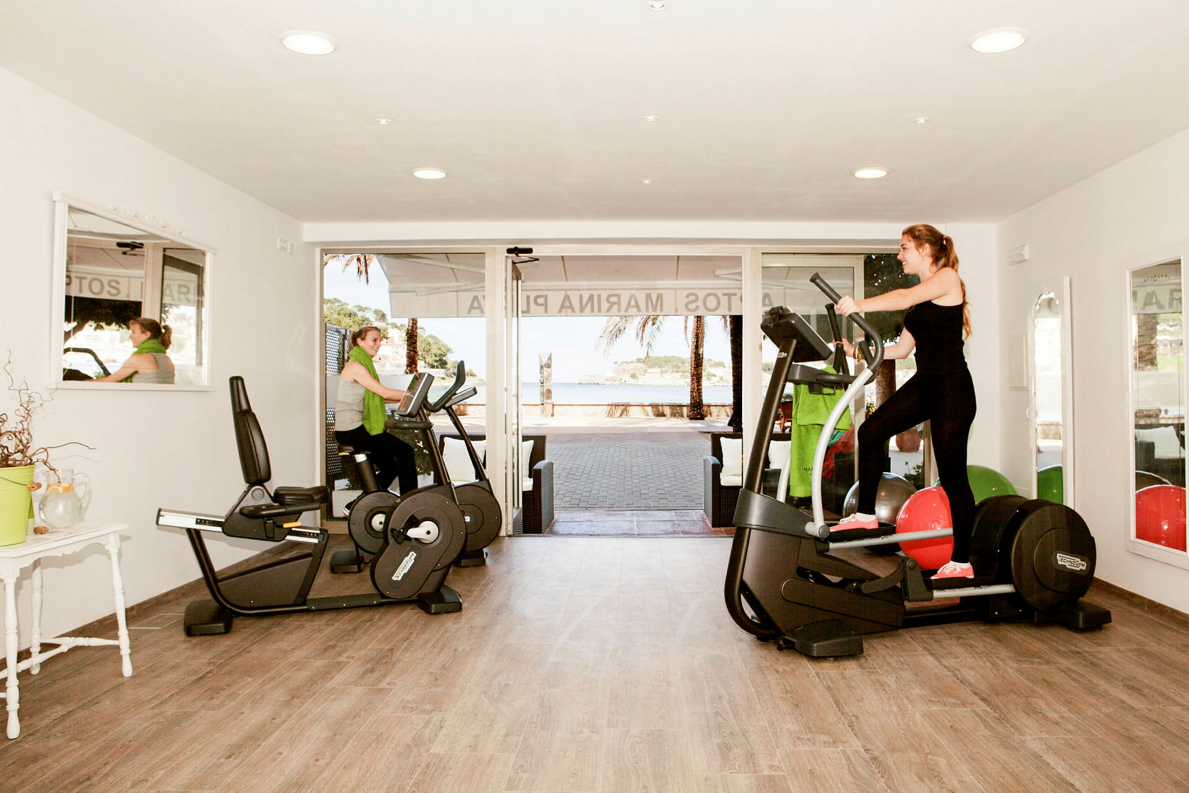 Ett gym med träningsmaskiner och fönster som vetter mot utsidan. (AI-genererad text)