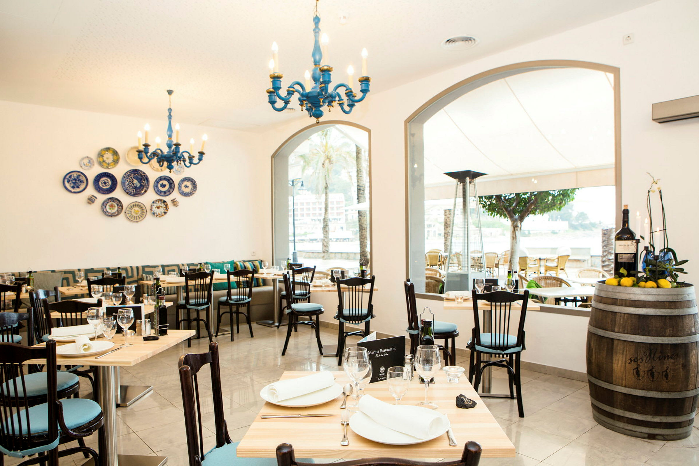 Bild av en restaurang med ljusa möbler och dekorationer samt utsikt mot en terrass. (AI-genererad text)