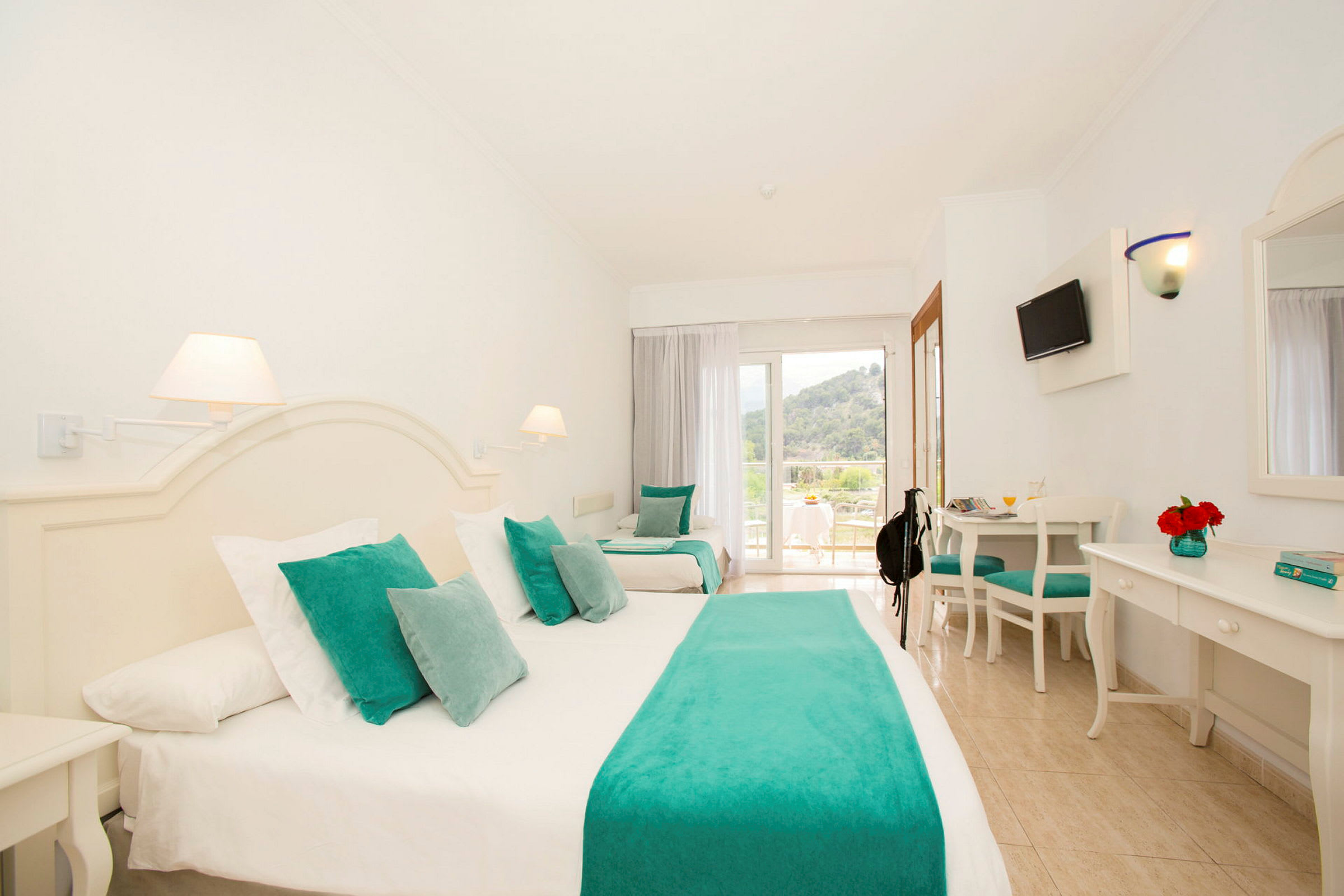 Hotellrum med vit inredning och turkosa textilier. (AI-genererad text)