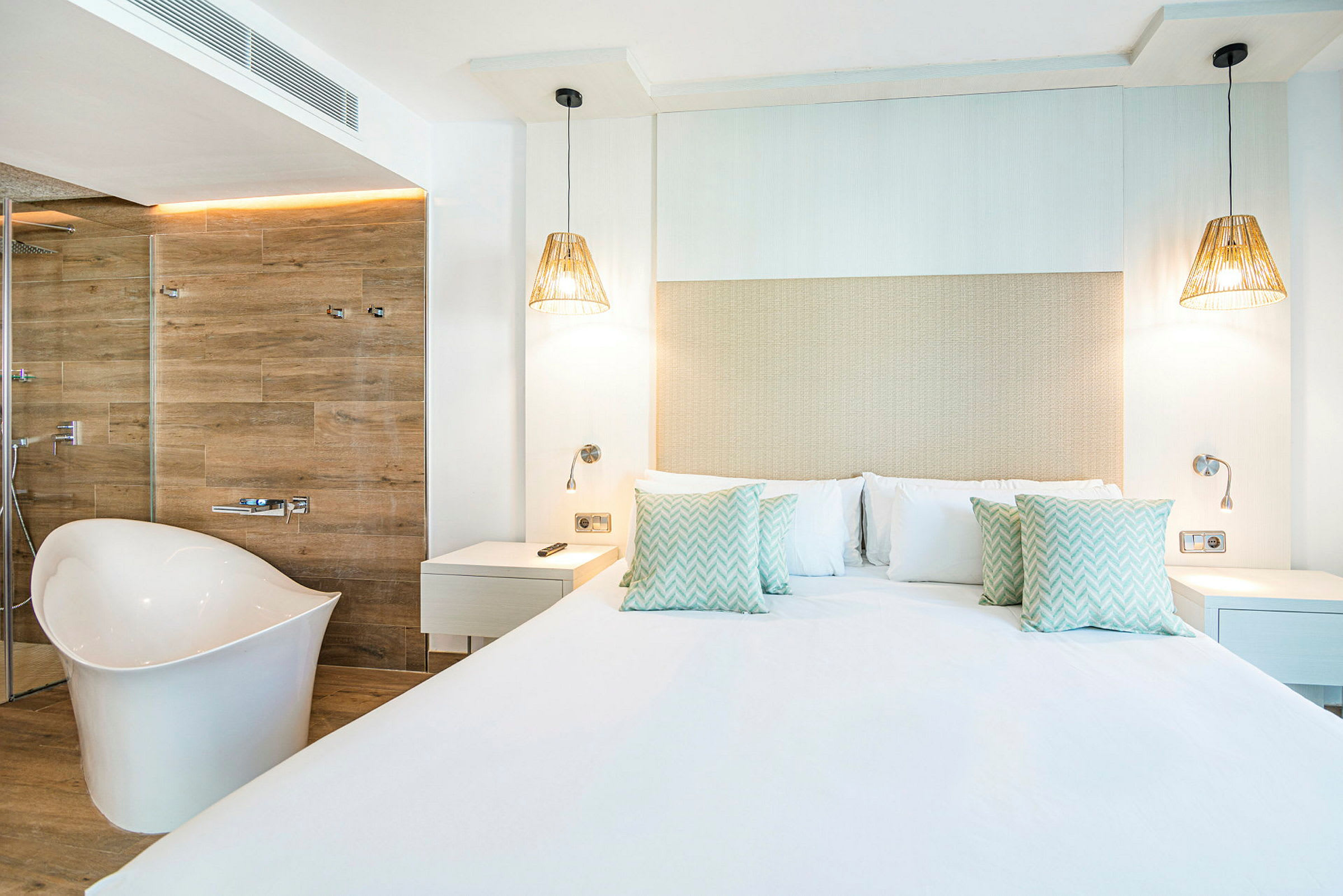 Ett modernt hotellrum med en stor säng, vita väggar och en fristående badkar. (AI-genererad text)