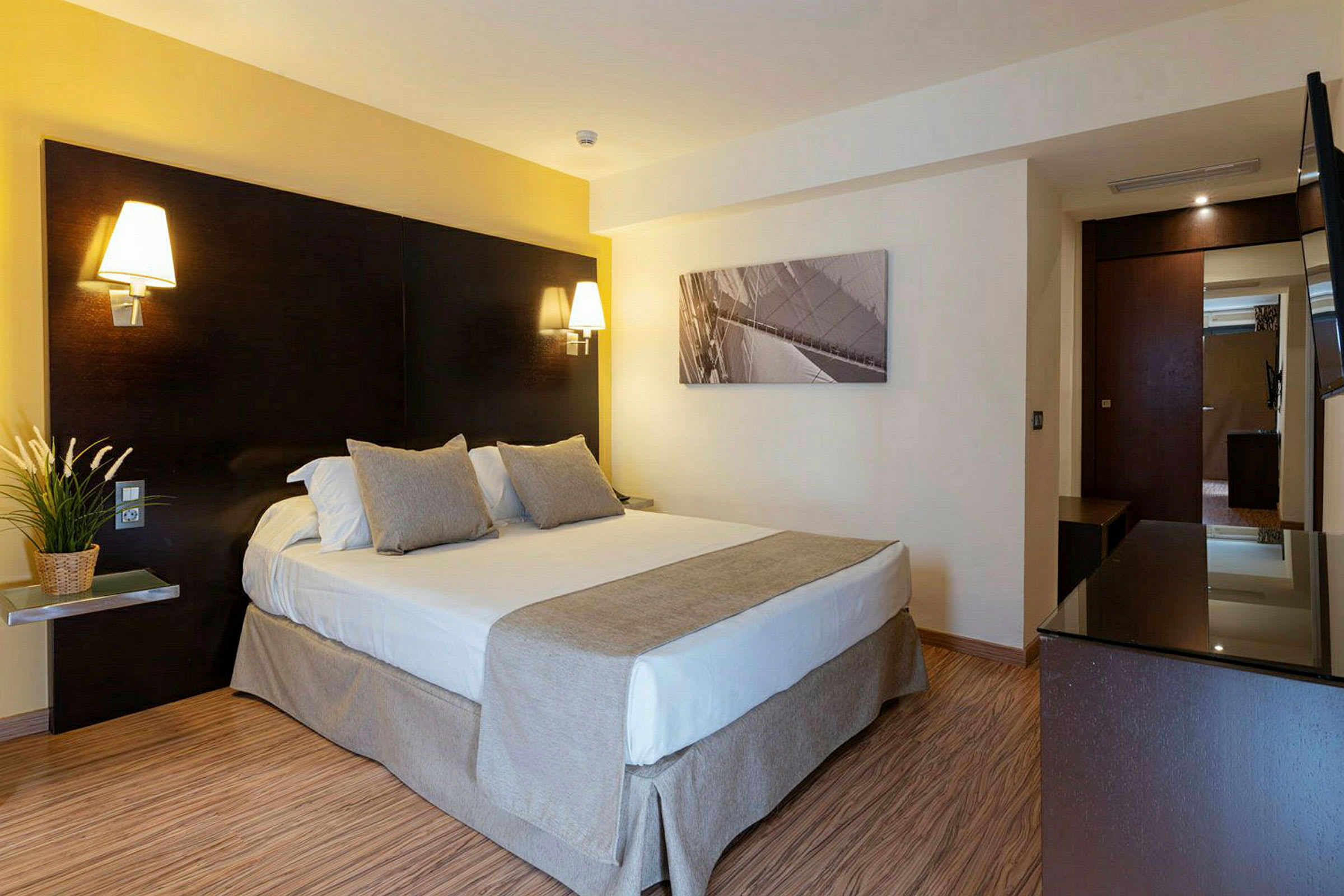 Ett hotellrum med en dubbelsäng, sänglampor och en tavla på väggen. (AI-genererad text)