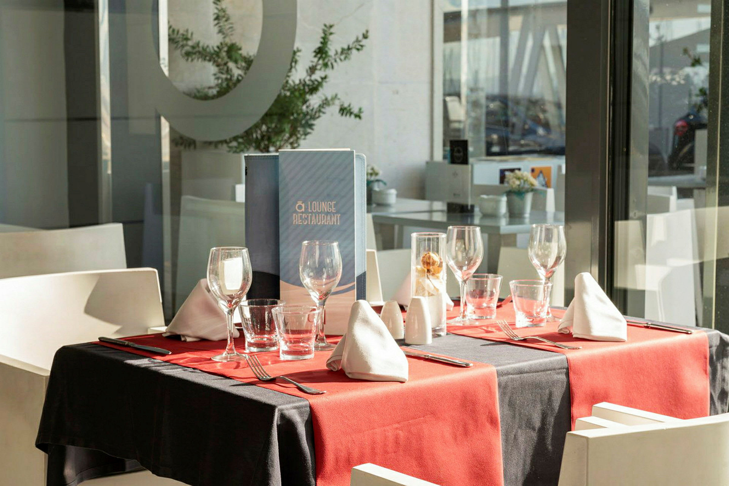 Ett dukat bord med glas, bestick och servetter i en restaurang. (AI-genererad text)