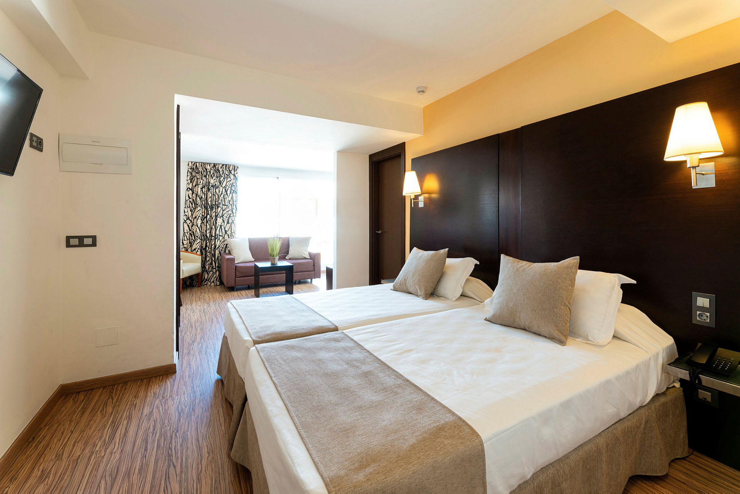 Hotel rum med två enkelsängar och ett sittområde. (AI-genererad text)