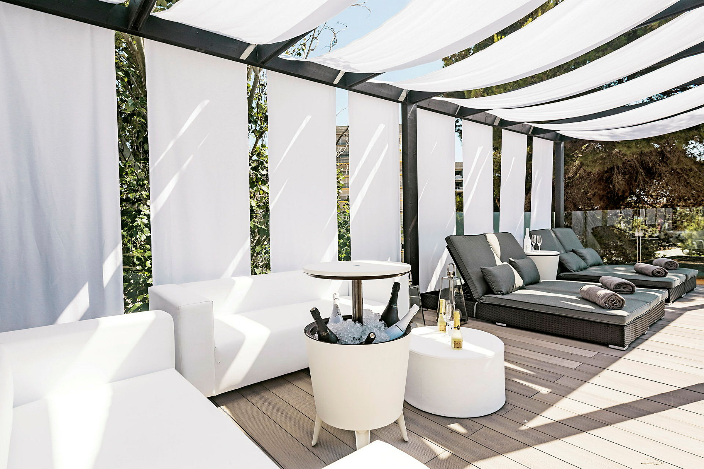 Utomhuslounge med vita soffor, solstolar och solskydd. (AI-genererad text)