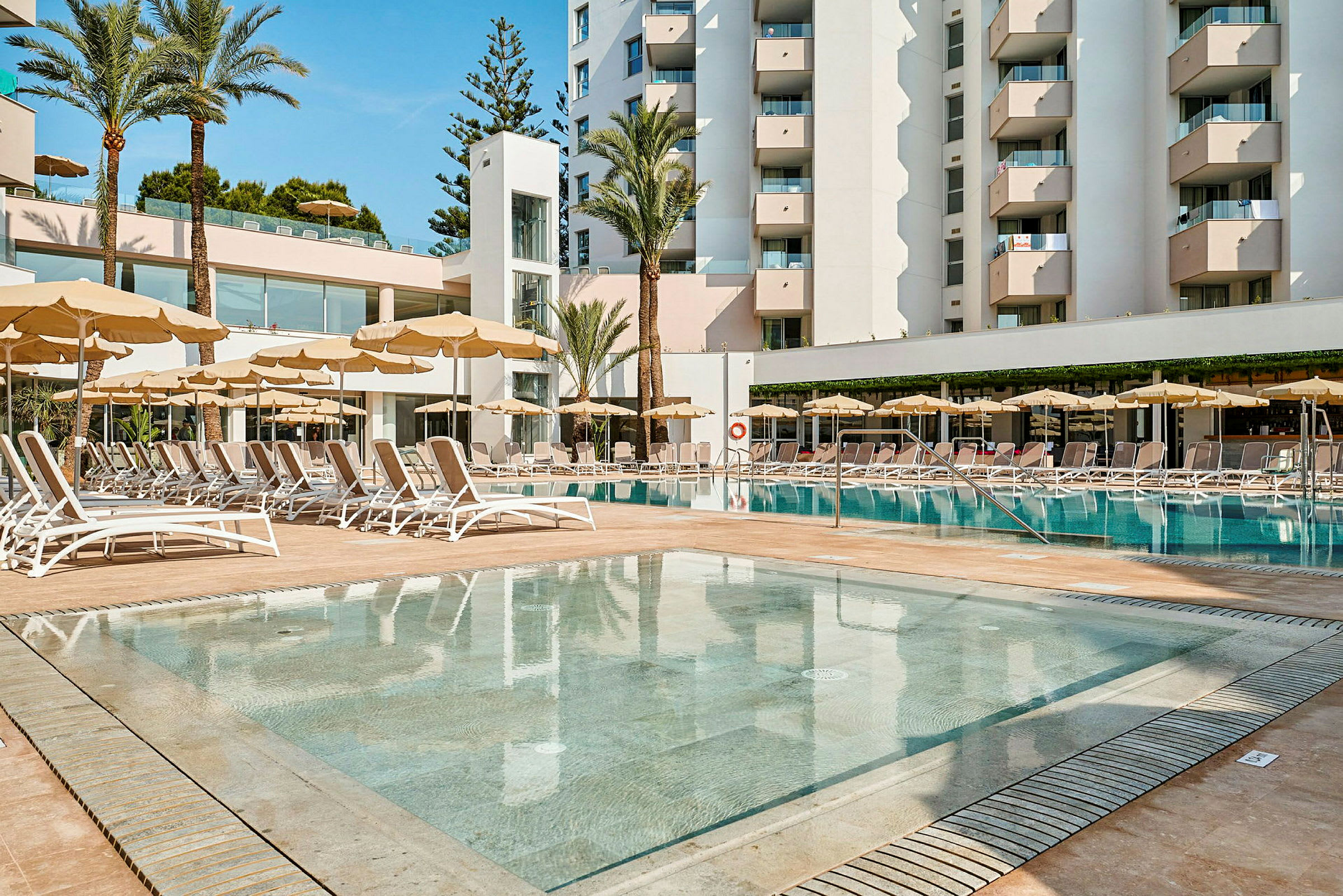 Hotellkomplex med pool och solstolar. (AI-genererad text)