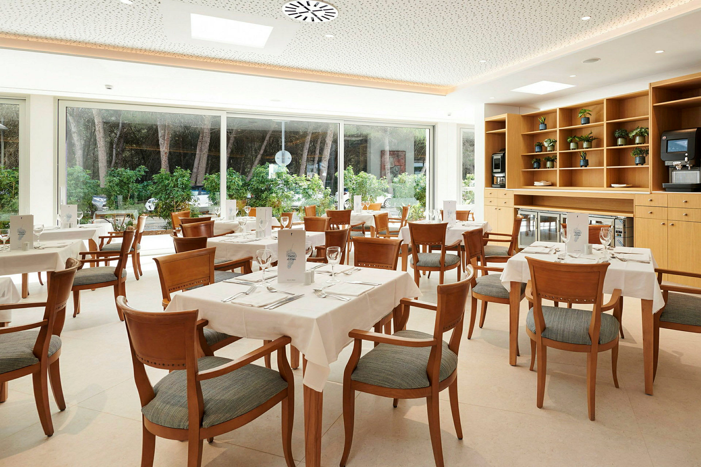 Bild av en ljus restaurang med flera dukade bord och stolar. (AI-genererad text)
