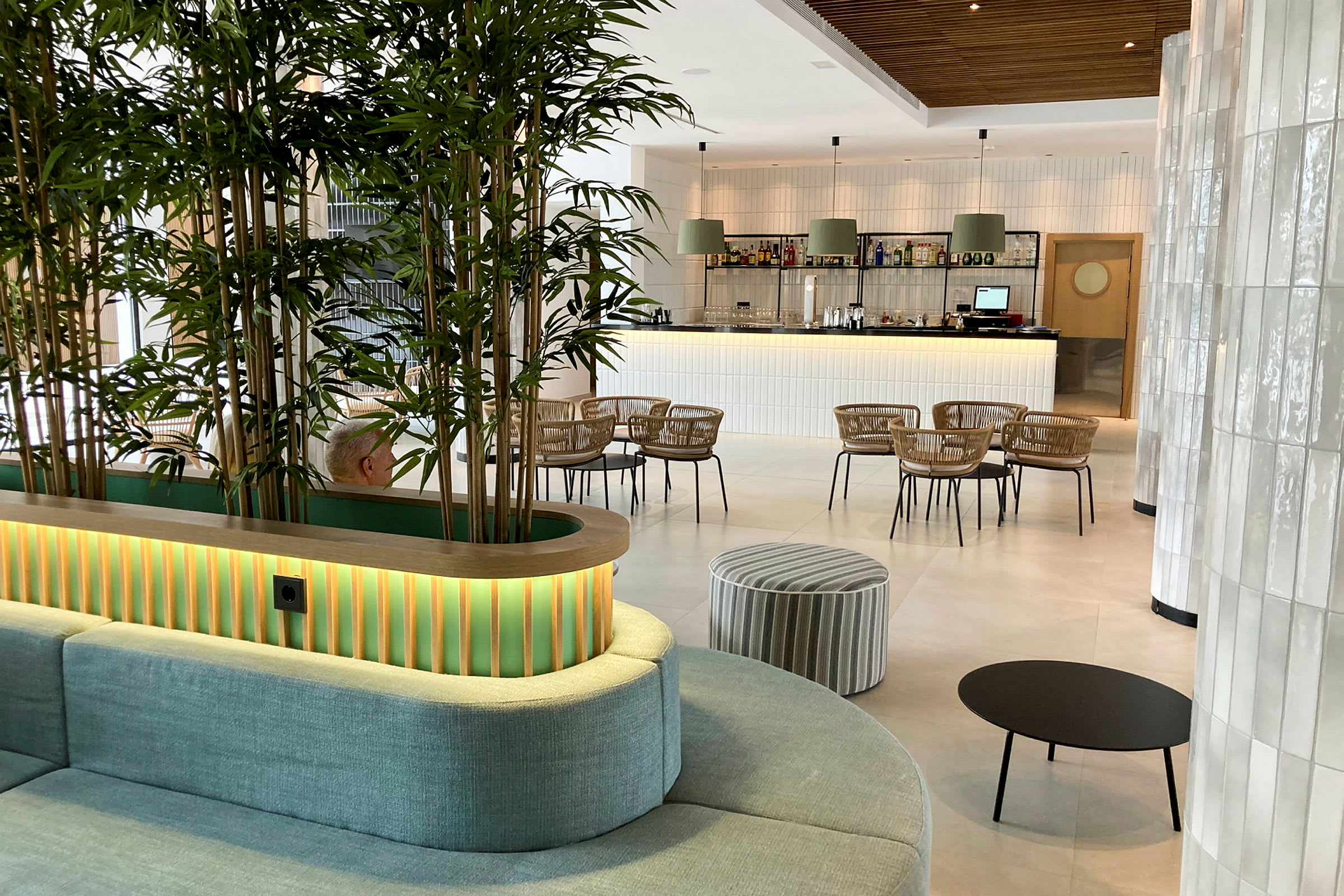 Inredningen i en modern lounge med gröna växter, sittmöbler och en bar i bakgrunden. (AI-genererad text)
