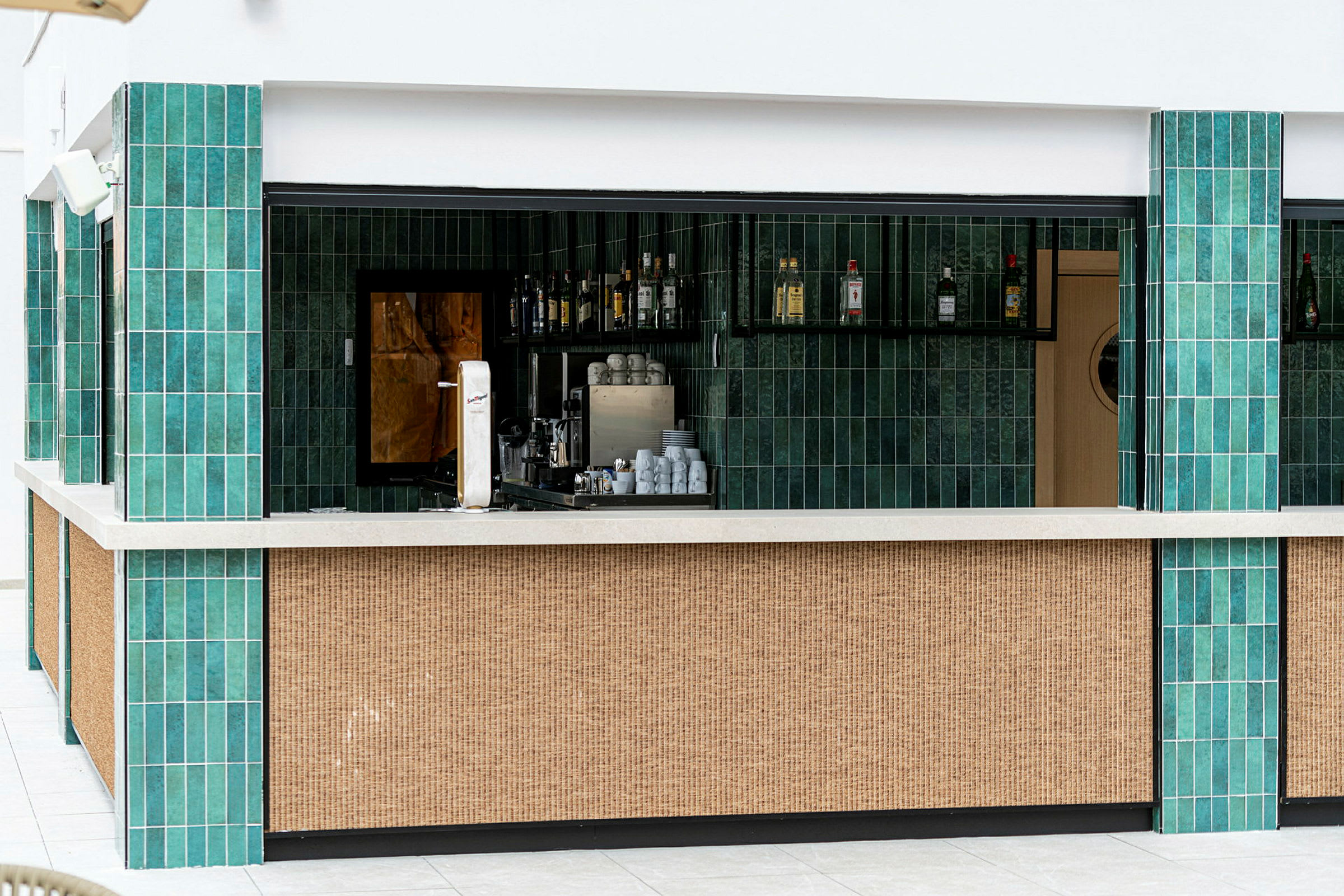 En bar med gröna kakelväggar och en ljus bardisk. (AI-genererad text)