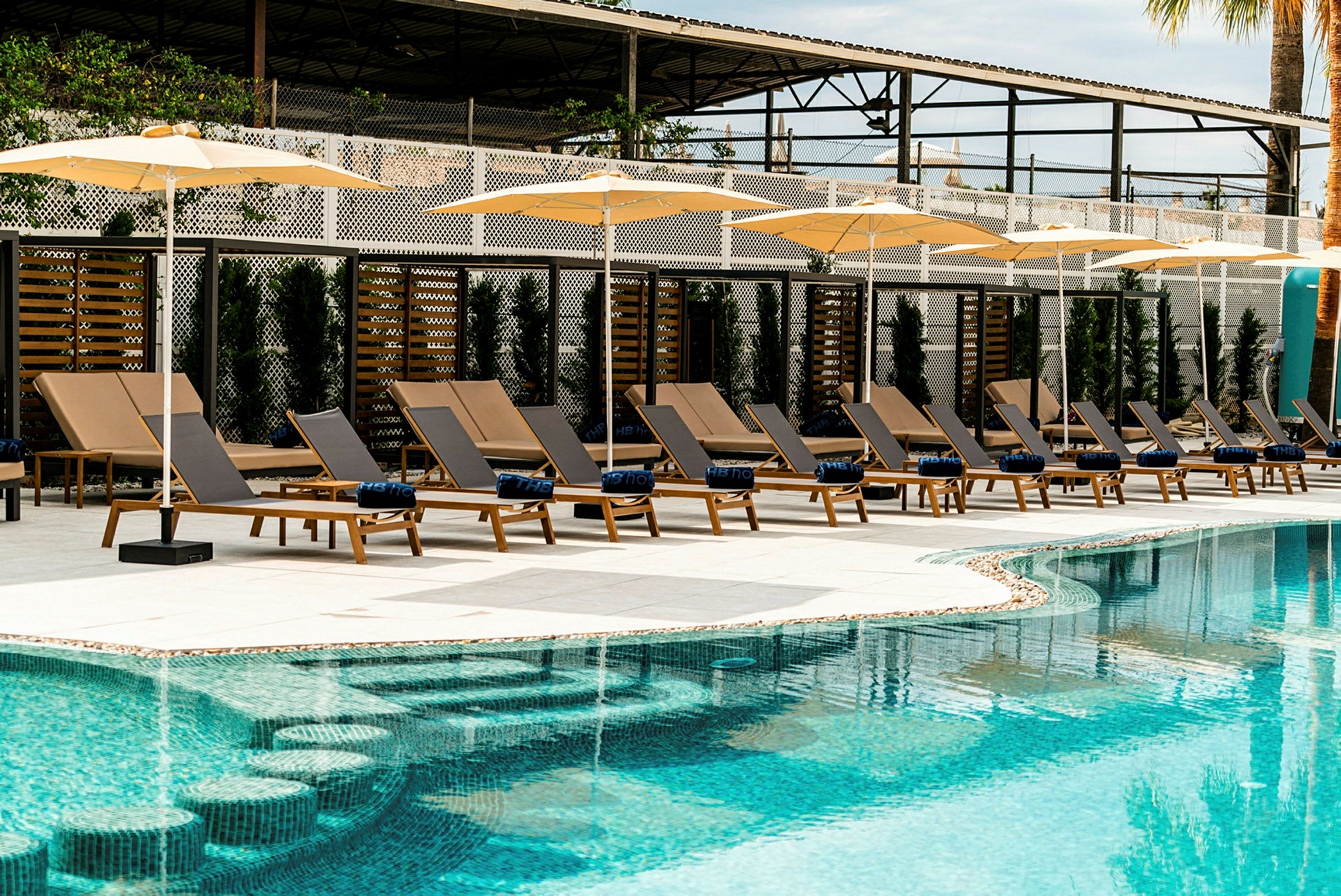 Solstolar med parasoller vid en pool. (AI-genererad text)