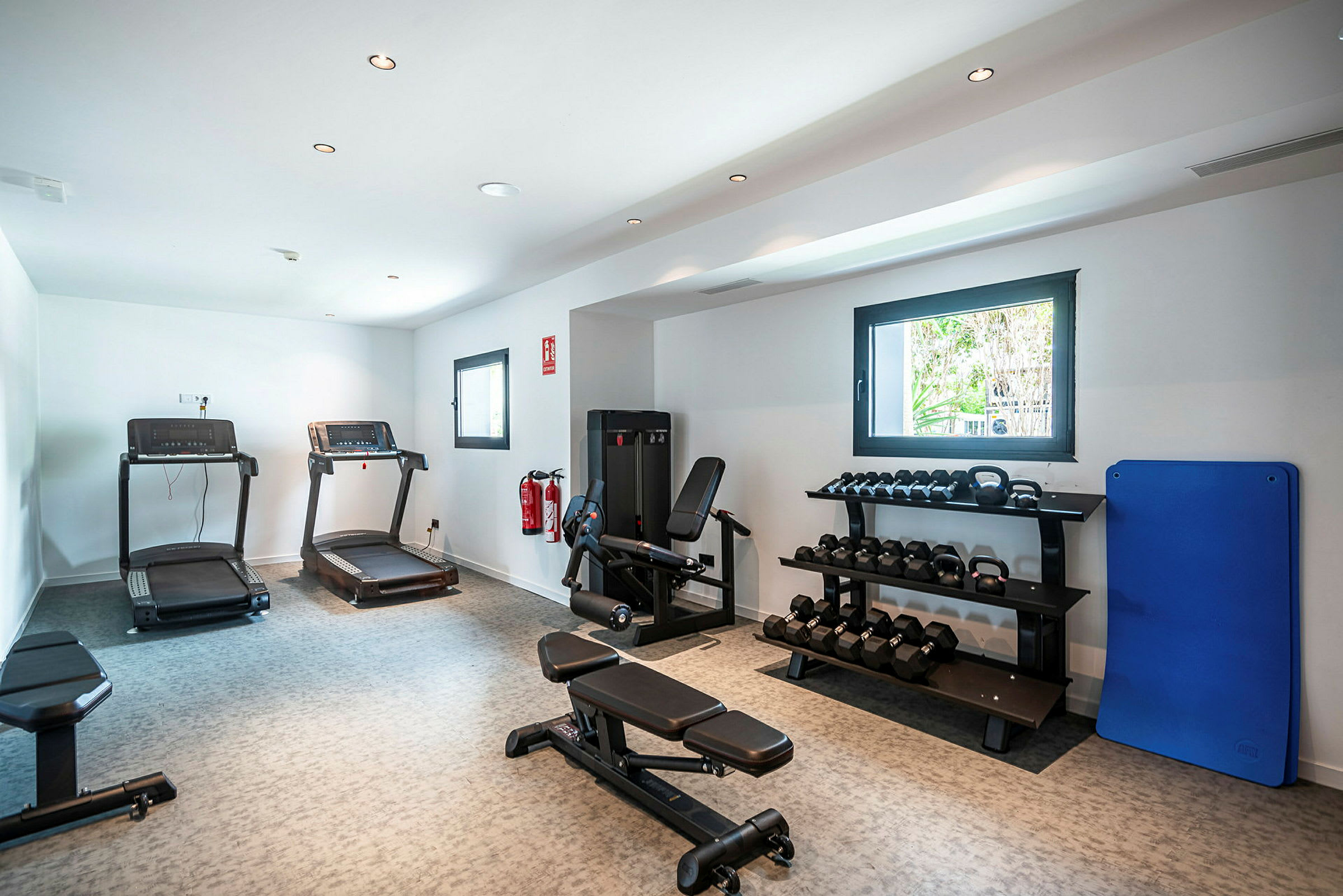 Ett gym med träningsmaskiner, hantlar på hyllor och löpband. (AI-genererad text)