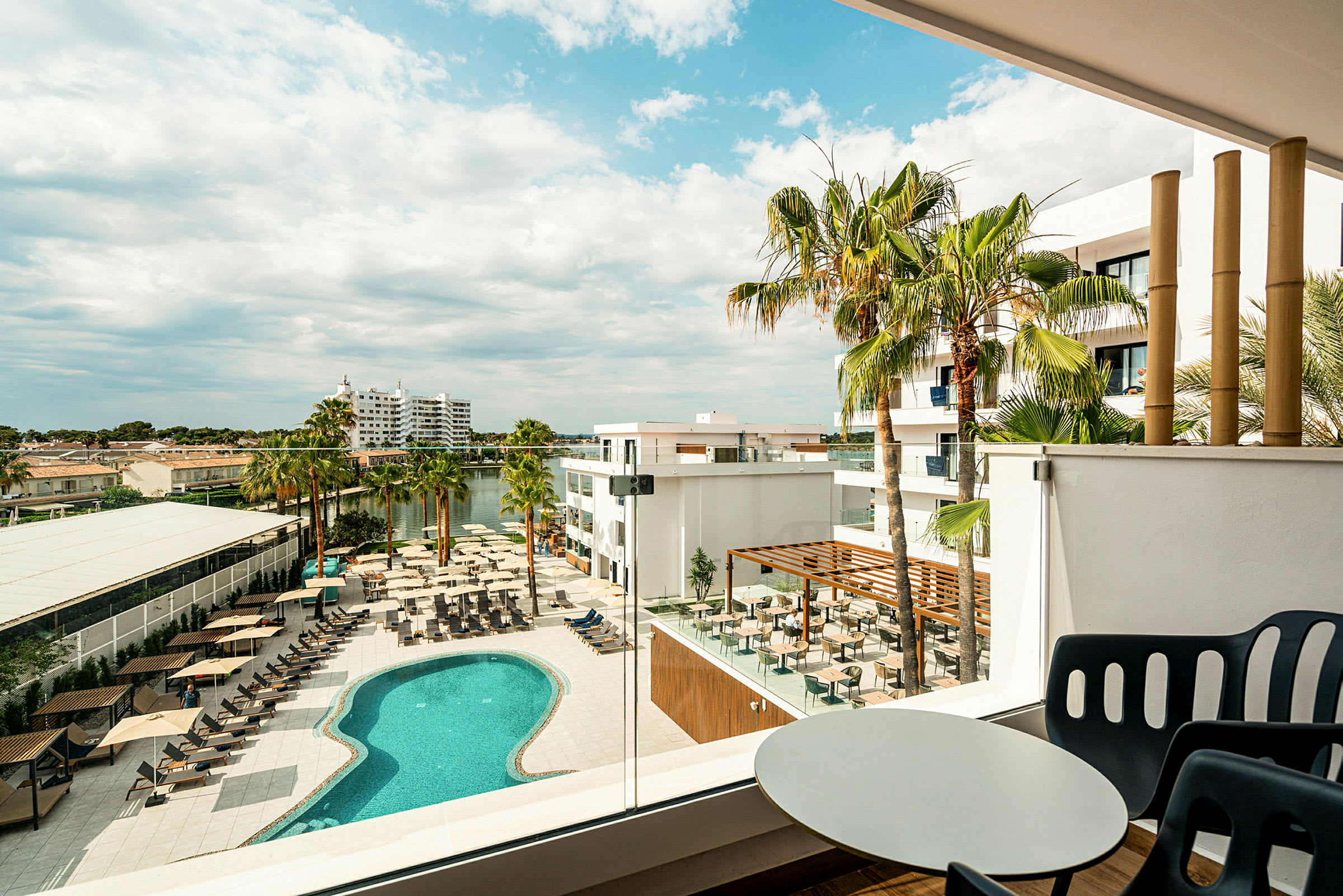 Utsikt över hotellkomplex med pool, solstolar och palmer. (AI-genererad text)