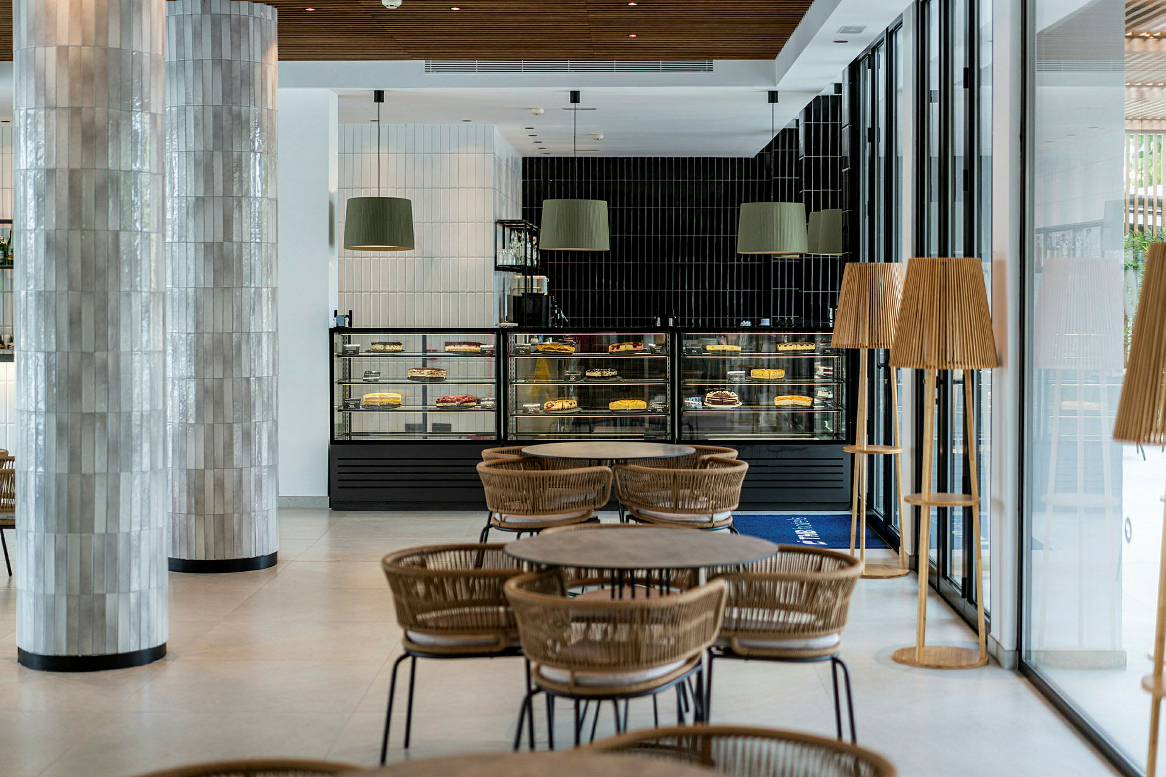 Ett modernt café med sittplatser och utställningsdiskar fyllda med tårtor och bakverk. (AI-genererad text)