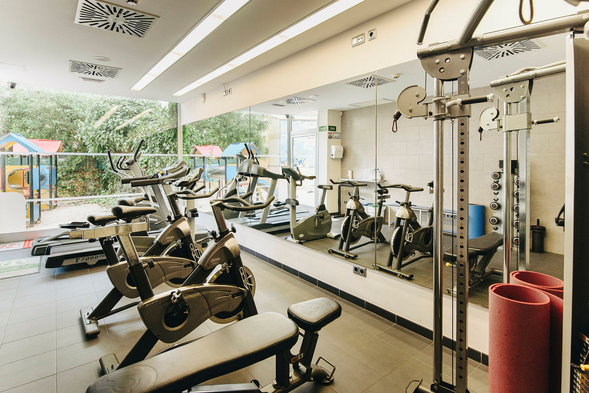 Ett gym med flera träningsmaskiner och speglar på väggen. (AI-genererad text)