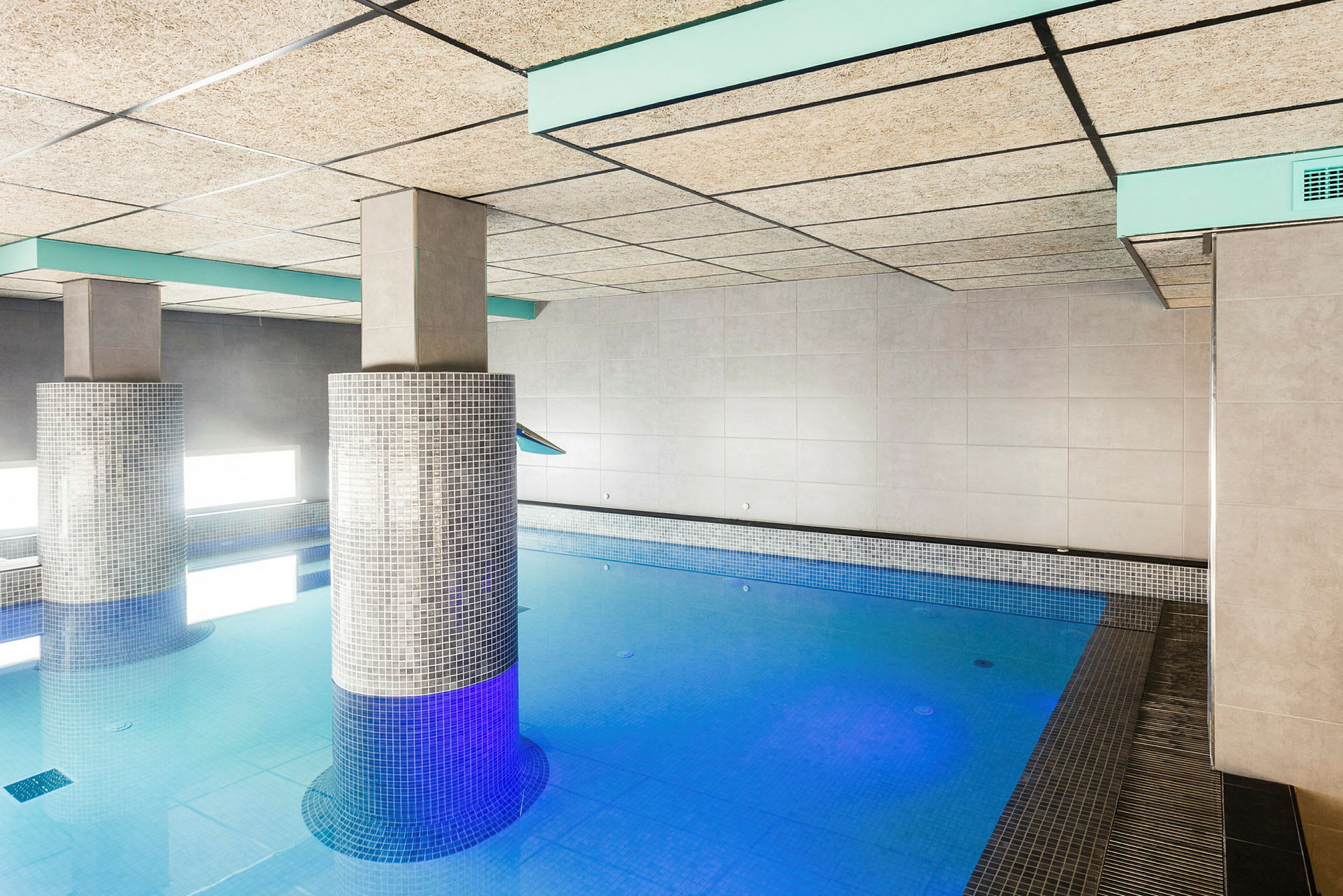 Inomhuspool med pelare klädda i mosaik. (AI-genererad text)