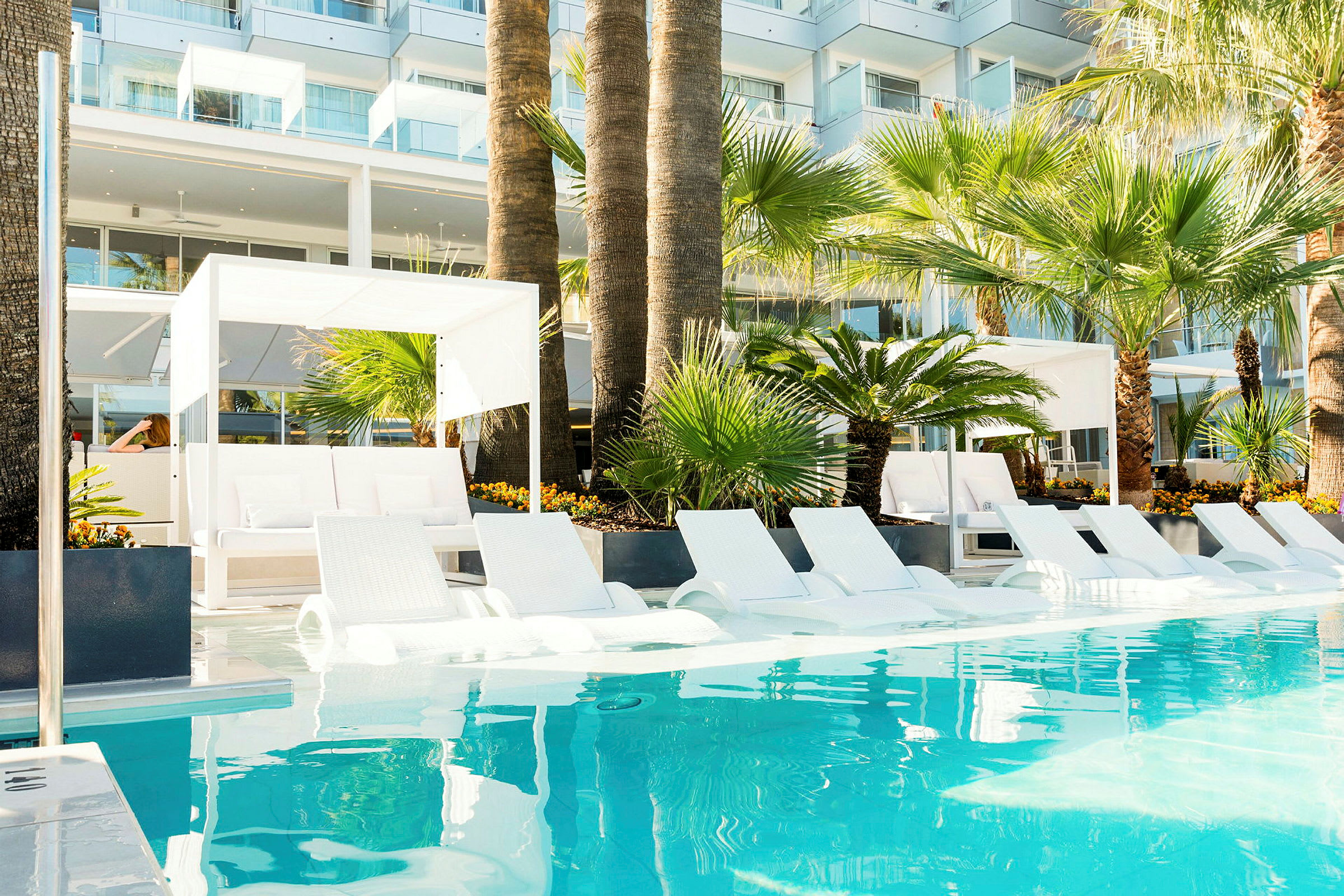 Poolområde med solstolar och palmer vid ett modernt hotell. (AI-genererad text)