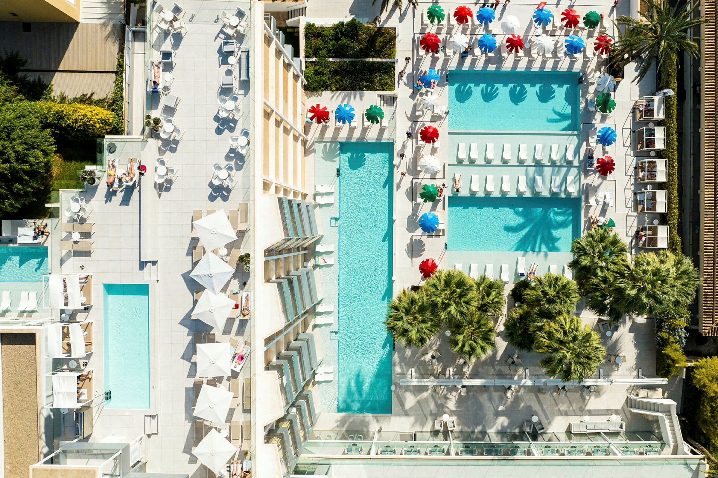 Luftfoto av en resort med poolområden, solstolar och parasoller. (AI-genererad text)