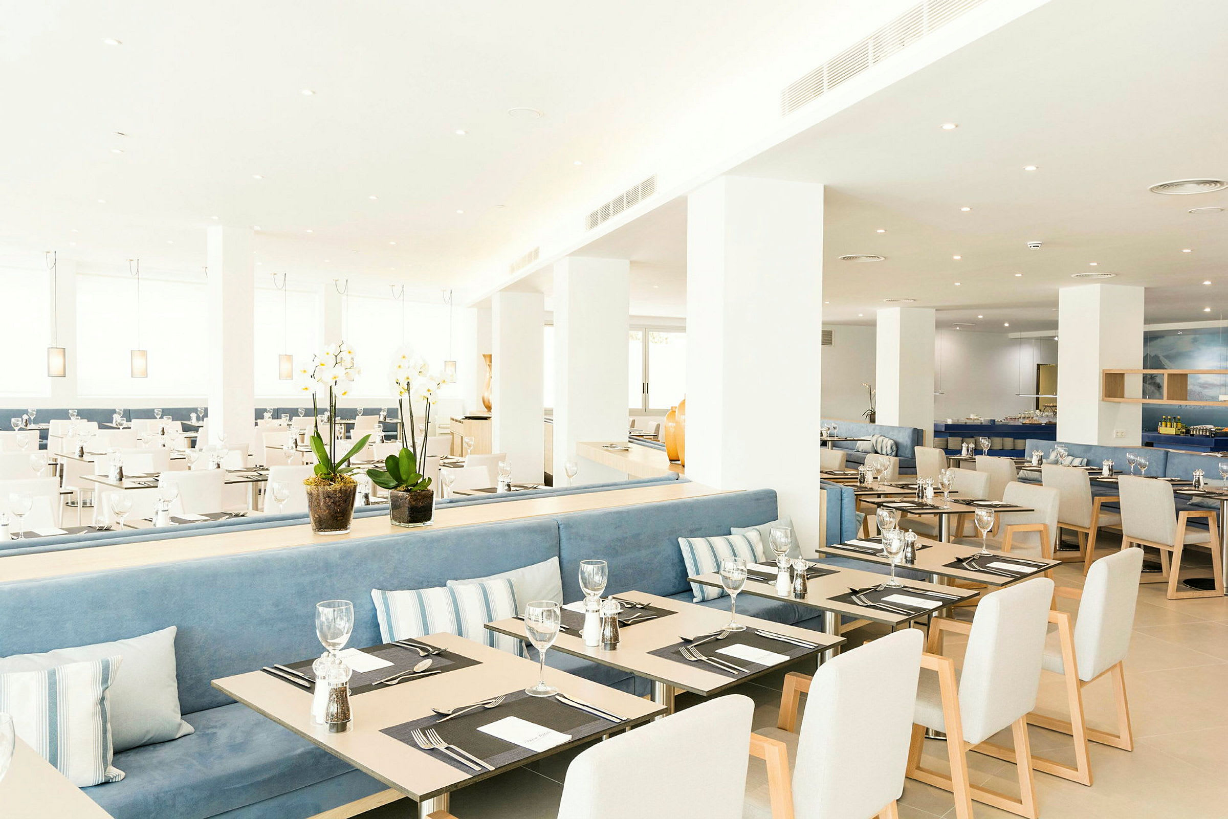 Ett modernt och ljust inrett restaurangutrymme med dukade bord och stolar. Växter på bordet tillför en dekorativ touch. (AI-genererad text)