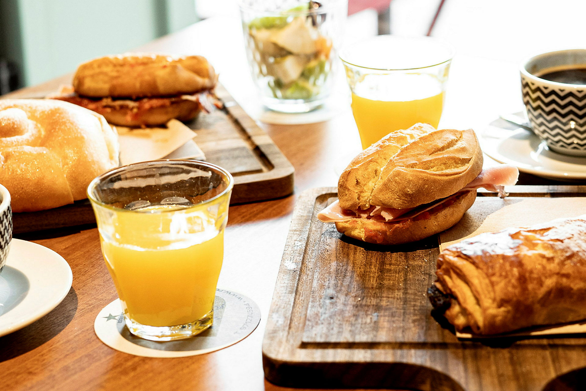 Bilden visar en frukostdukning med bröd, croissanter, apelsinjuice och kaffe på bordet. (AI-genererad text)