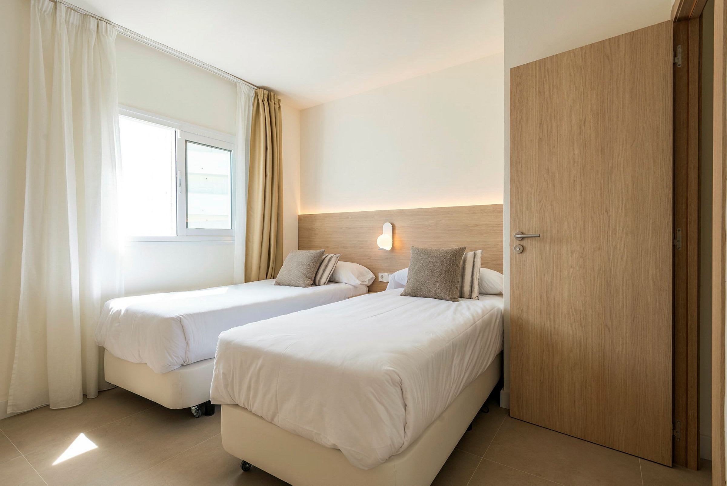 Hotellrum med två enkelsängar och en vägglampa. (AI-genererad text)