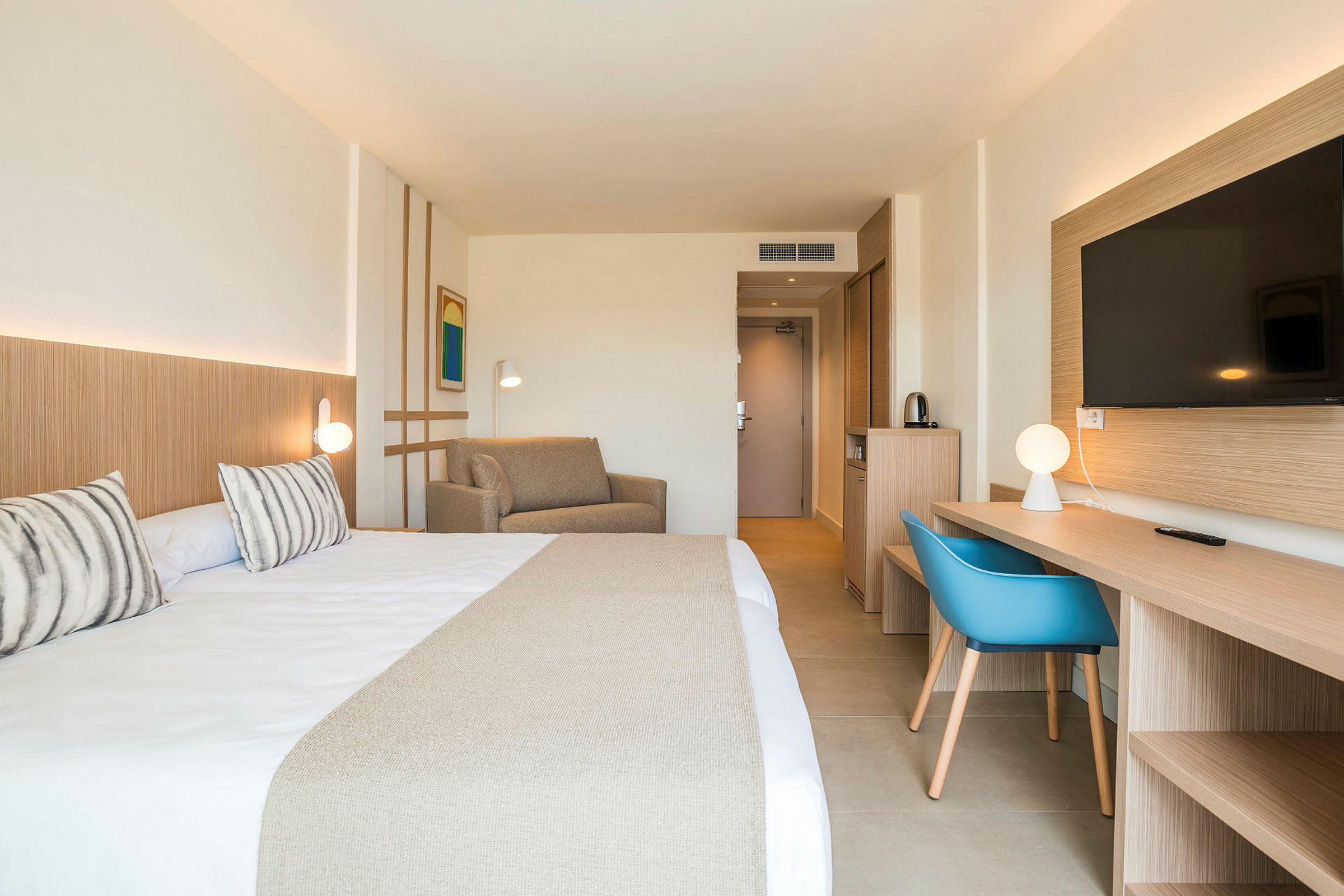Hotellrum med dubbelsäng, soffa, arbetsbord och TV. (AI-genererad text)