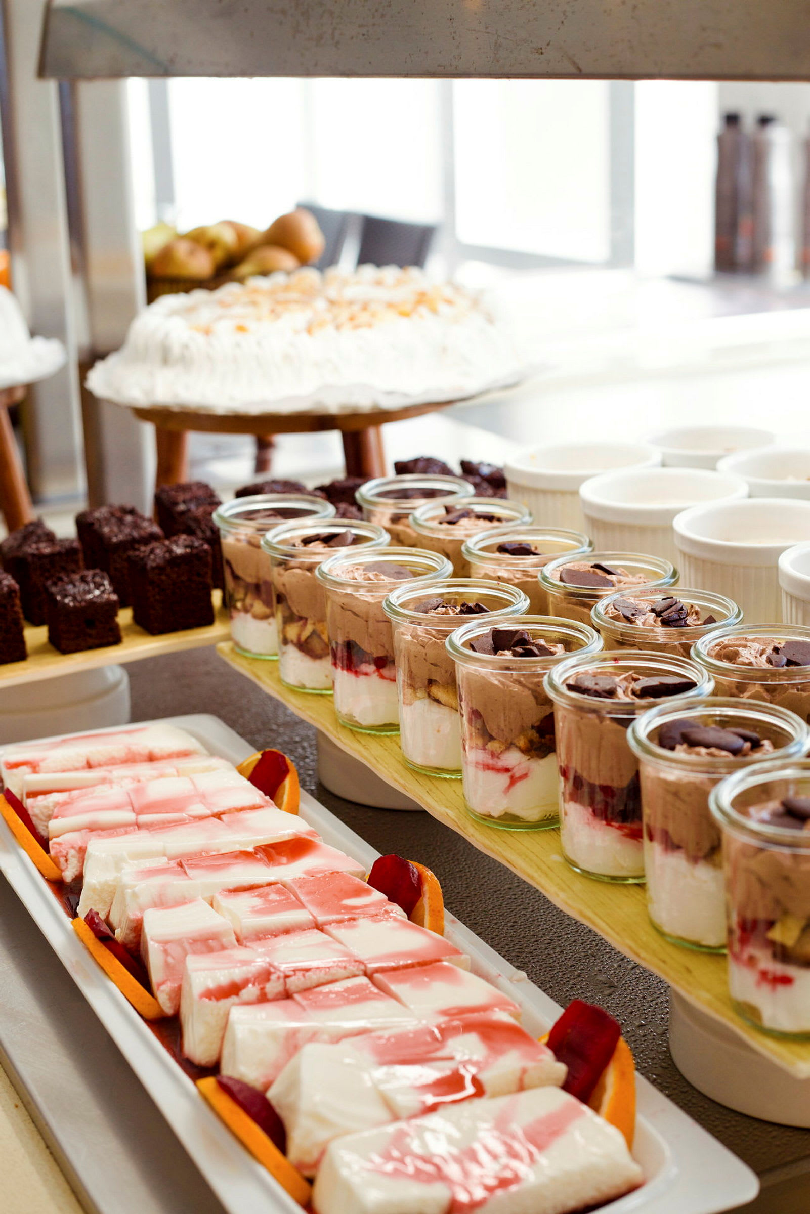 Bild på ett dessertbord med olika desserter såsom tårta, bakverk, och glasburkar med mousse. (AI-genererad text)