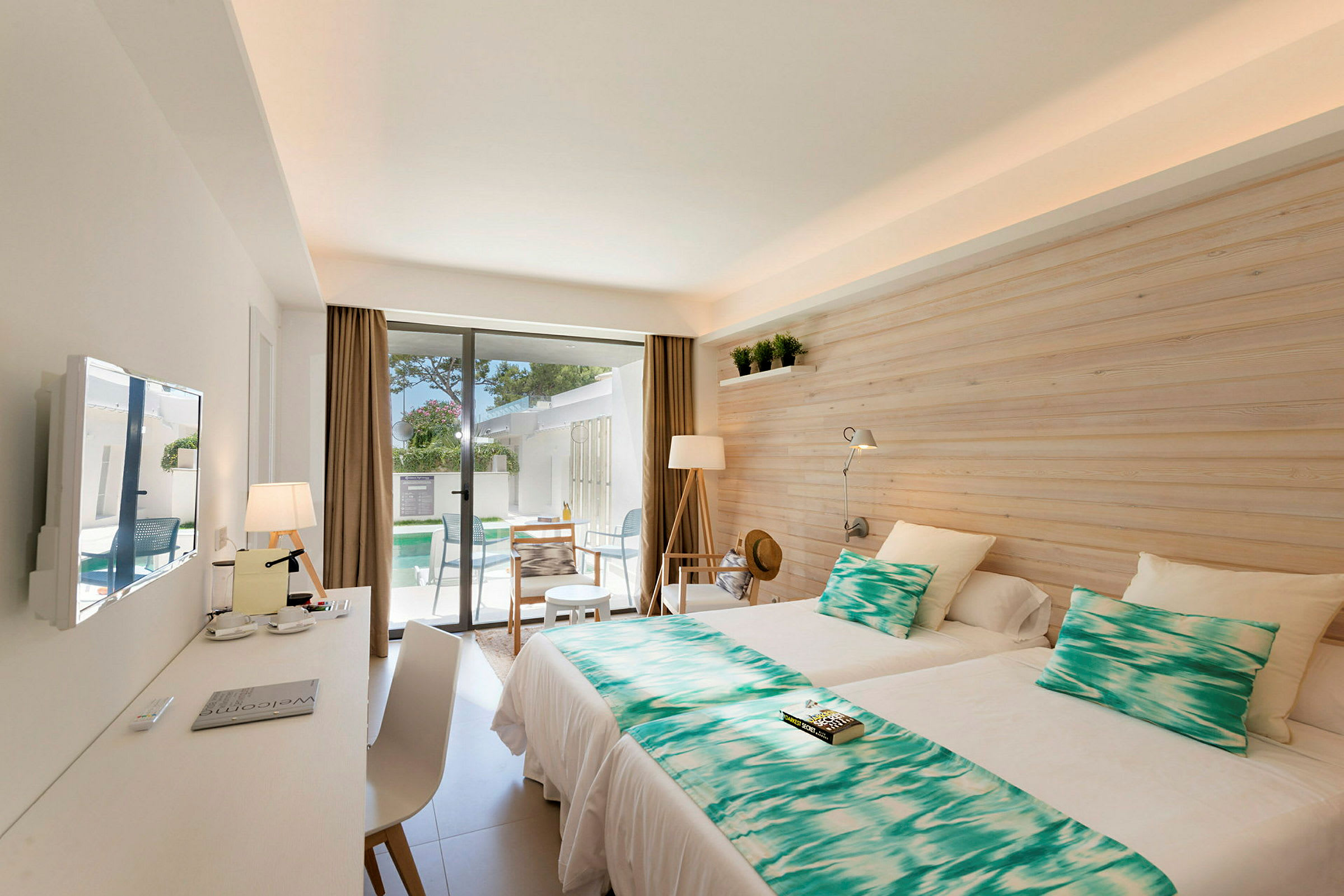 Modernt hotellrum med två enkelsängar och utsikt mot en terrass. (AI-genererad text)