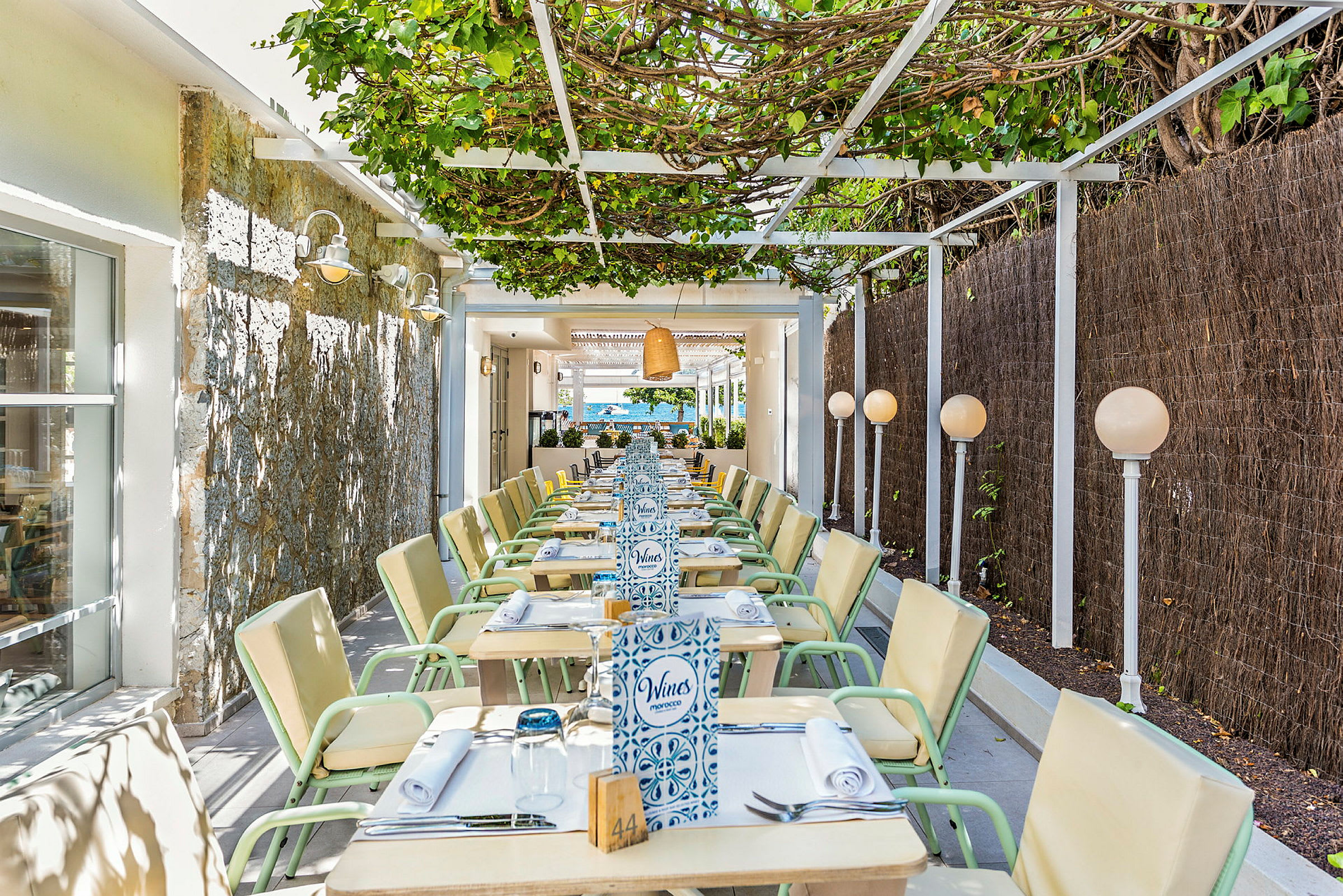 En utomhusrestaurang med sittplatser under en pergola. (AI-genererad text)