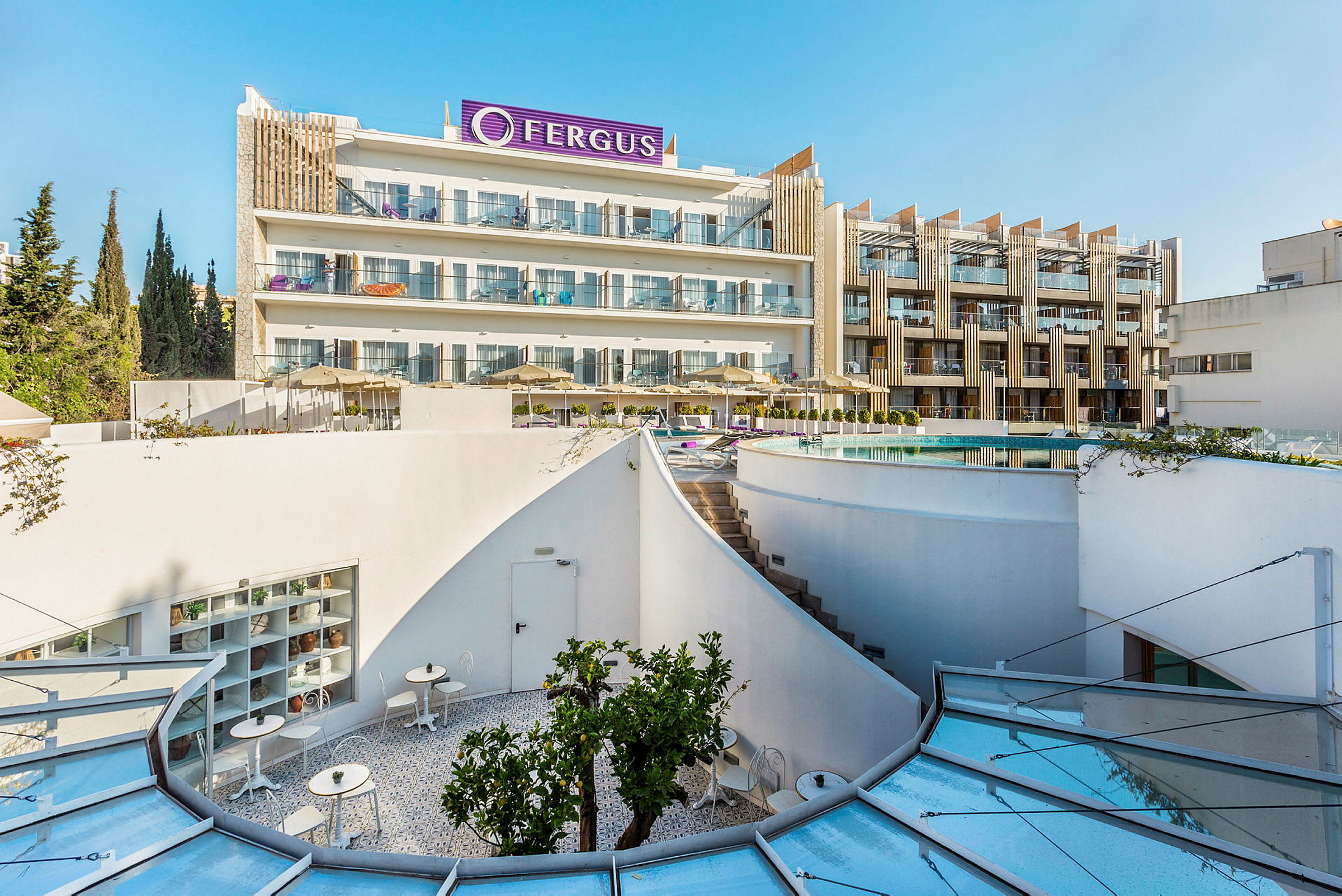 Fotografi av hotellet Fergus med en modern byggnad, pool och möblerade terrasser. (AI-genererad text)
