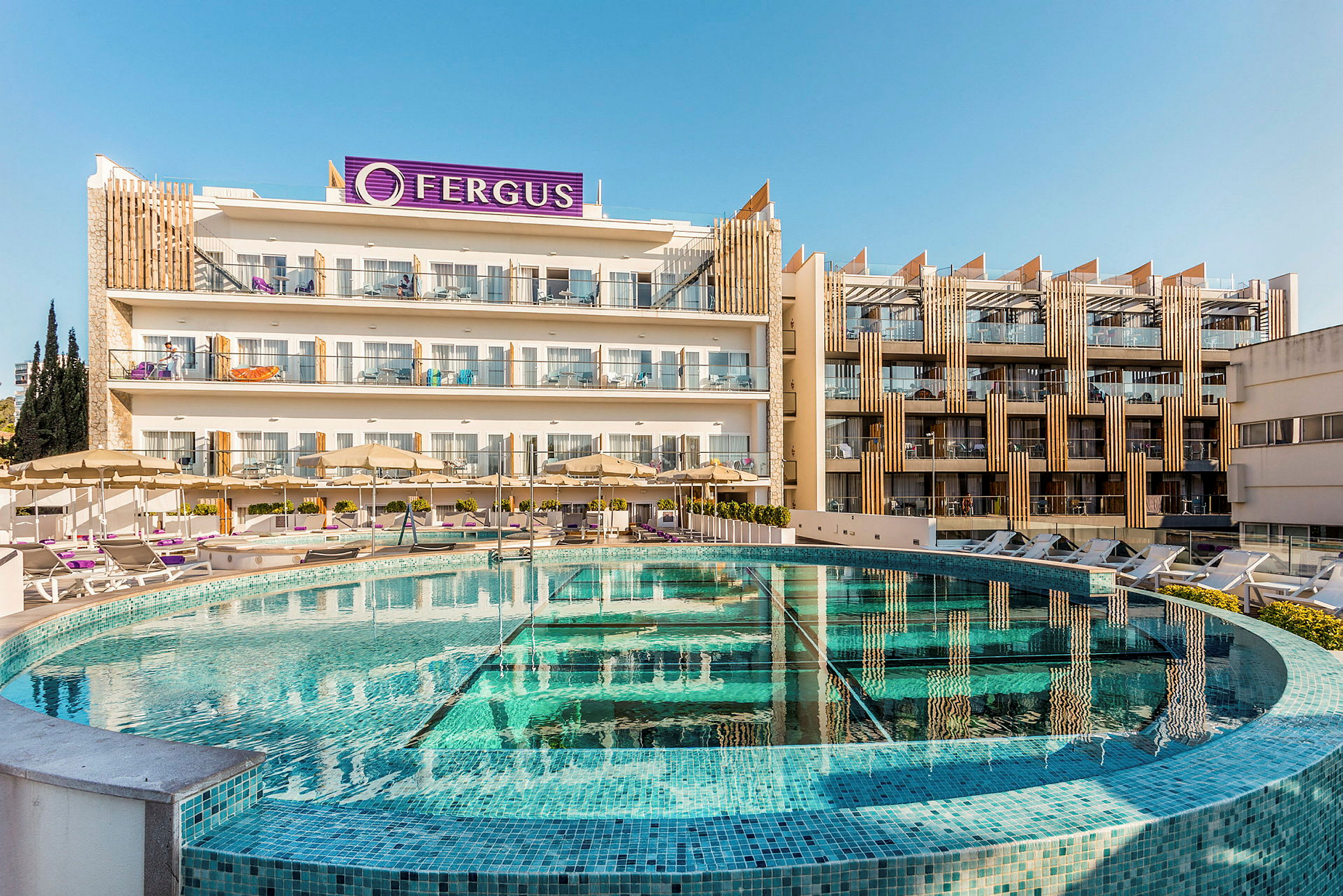 Hotellets byggnad med pool och solstolar i förgrunden. (AI-genererad text)