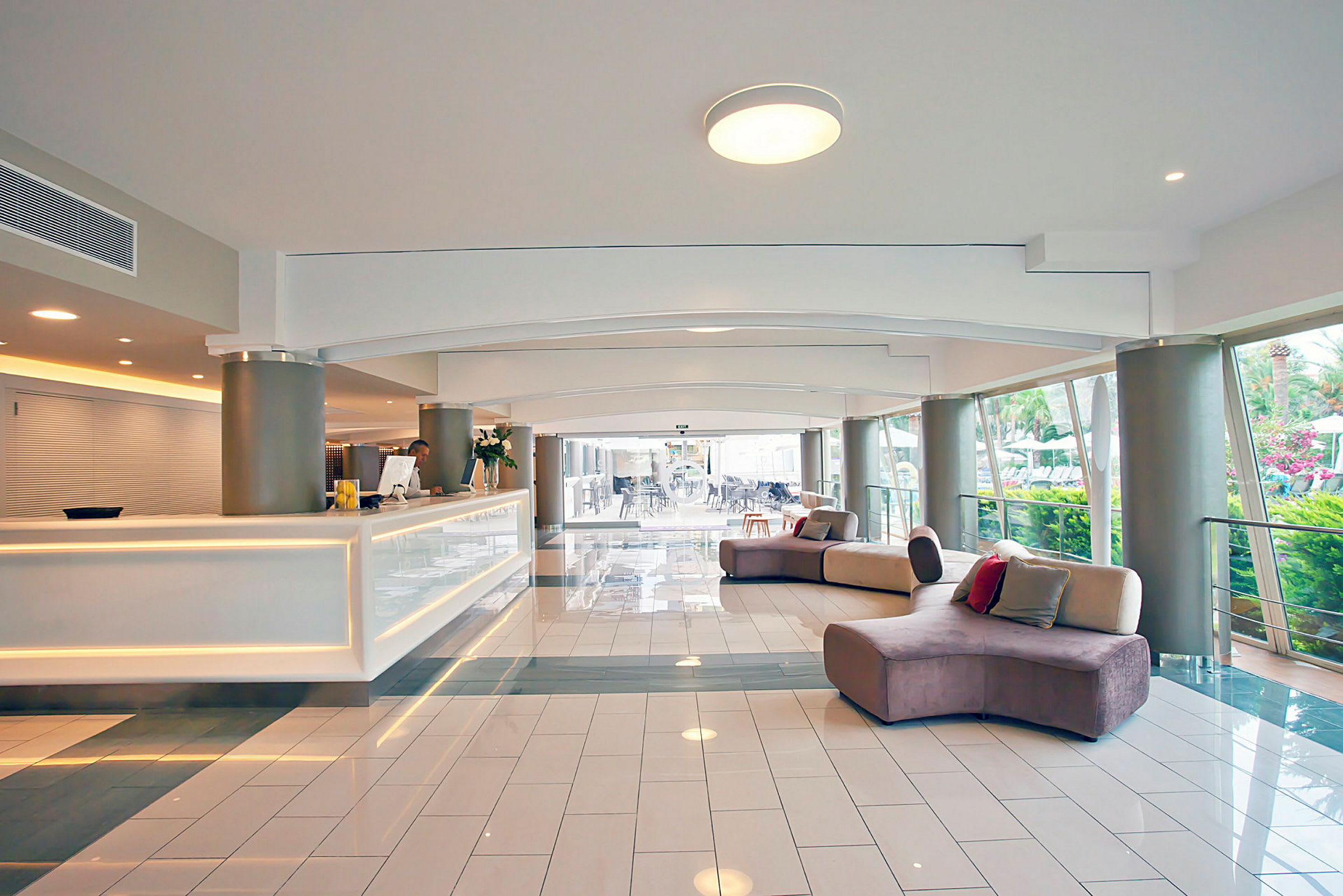 Hotellreception med vit disk och soffor i ett modernt och ljust rum. (AI-genererad text)