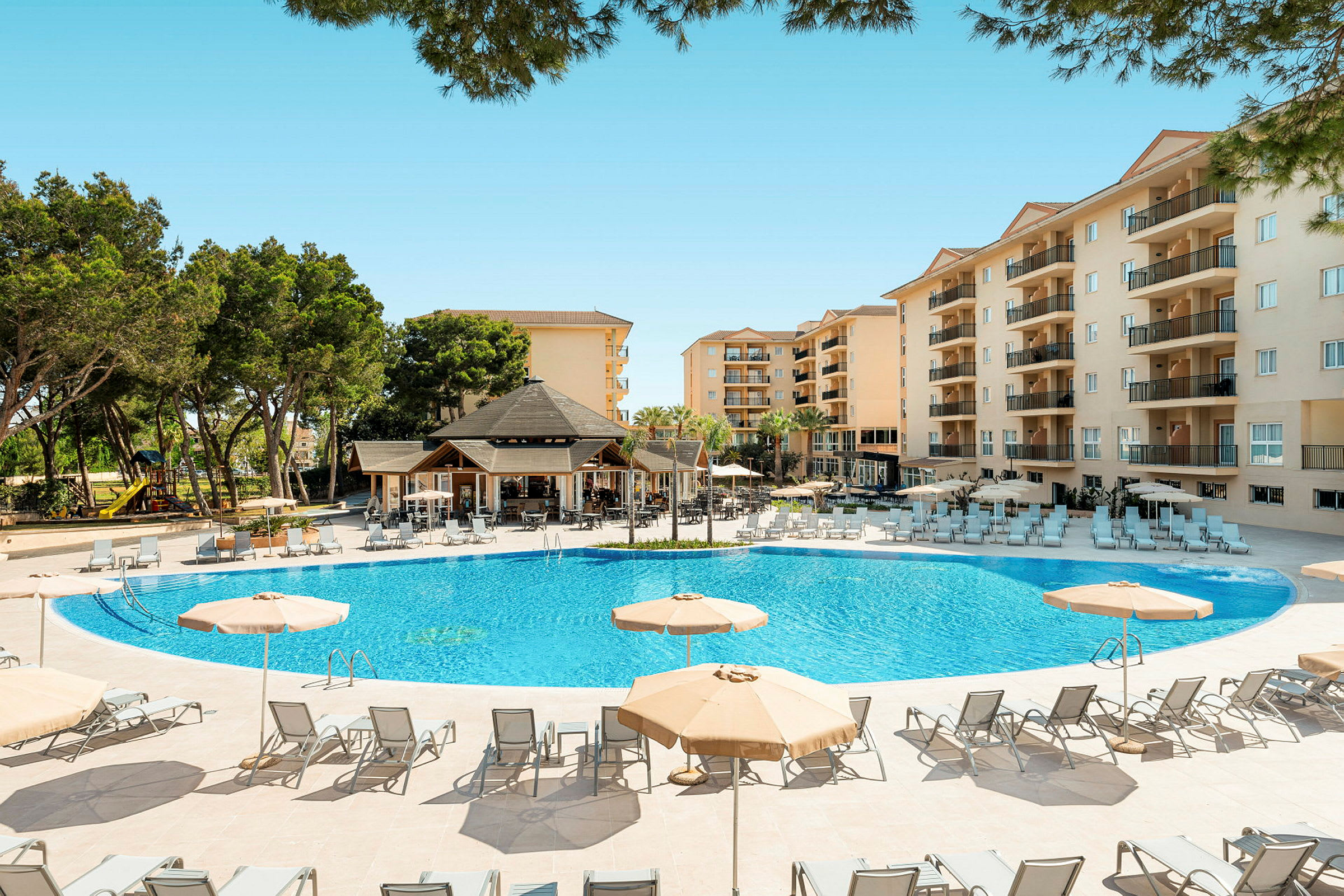 Utomhuspool med solstolar och parasoller, hotellbyggnader i bakgrunden. (AI-genererad text)