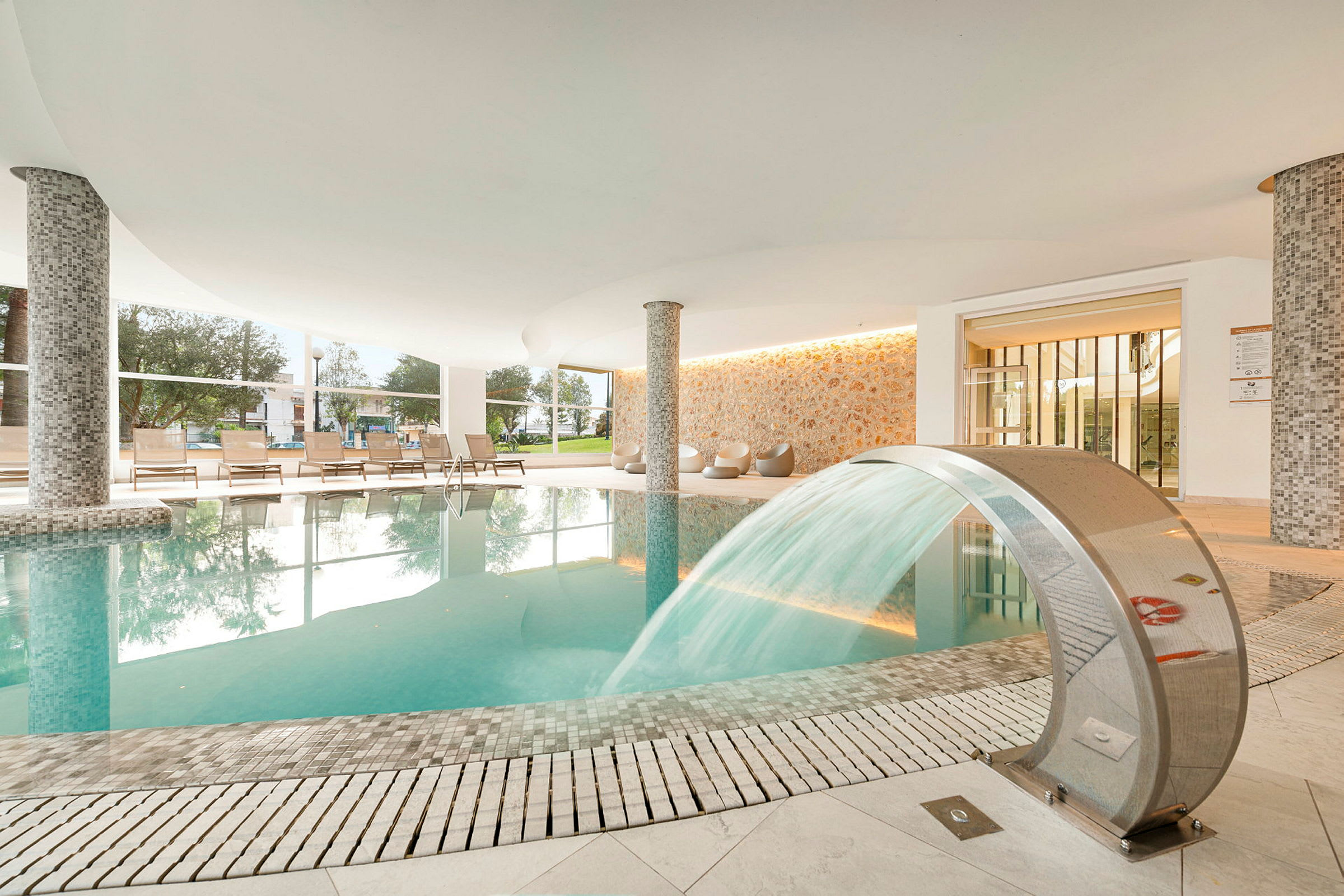 Inomhuspool med vattenfall och vilstolar. (AI-genererad text)
