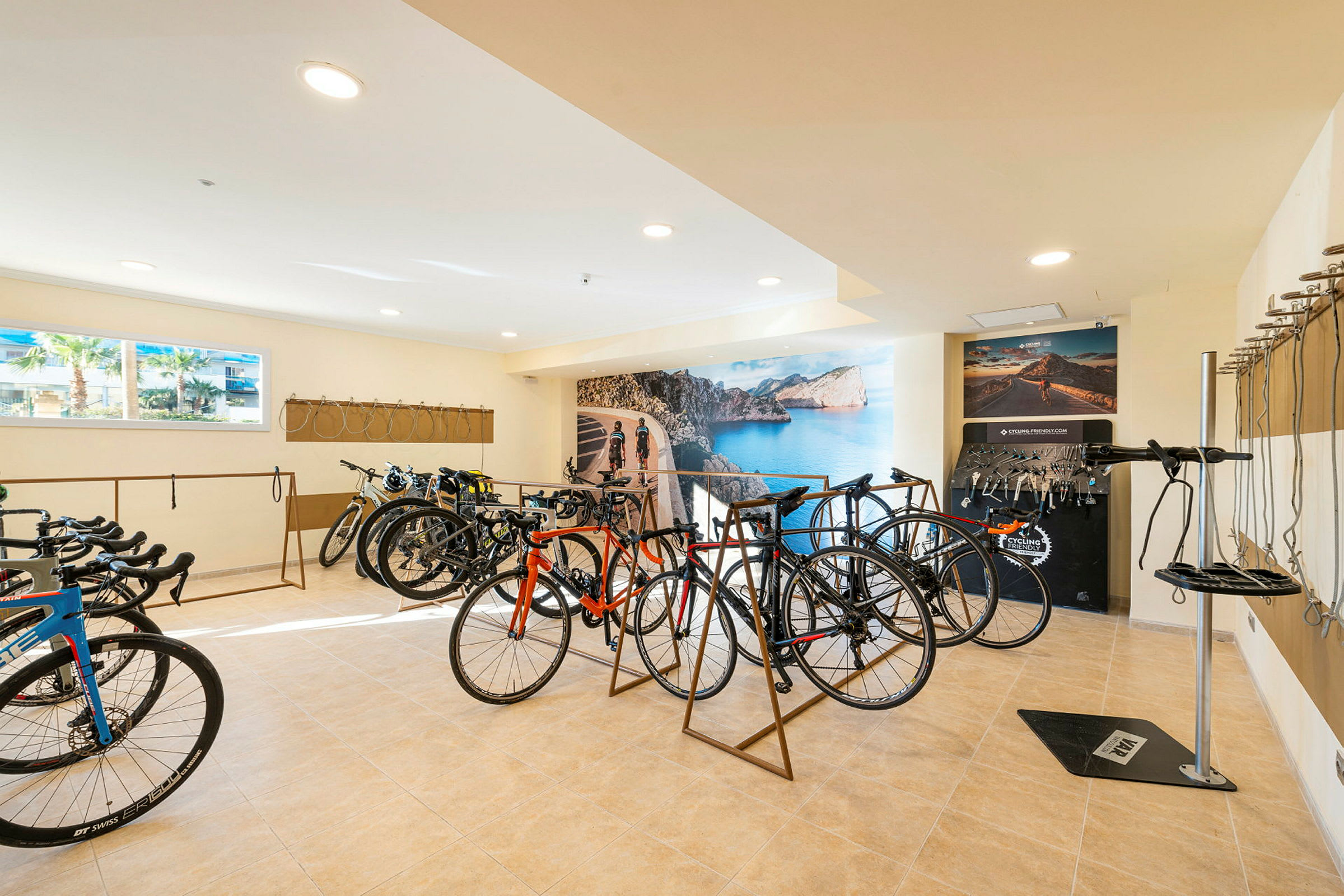 Ett rum med flera cyklar och en stor väggbild föreställande en kustväg. (AI-genererad text)