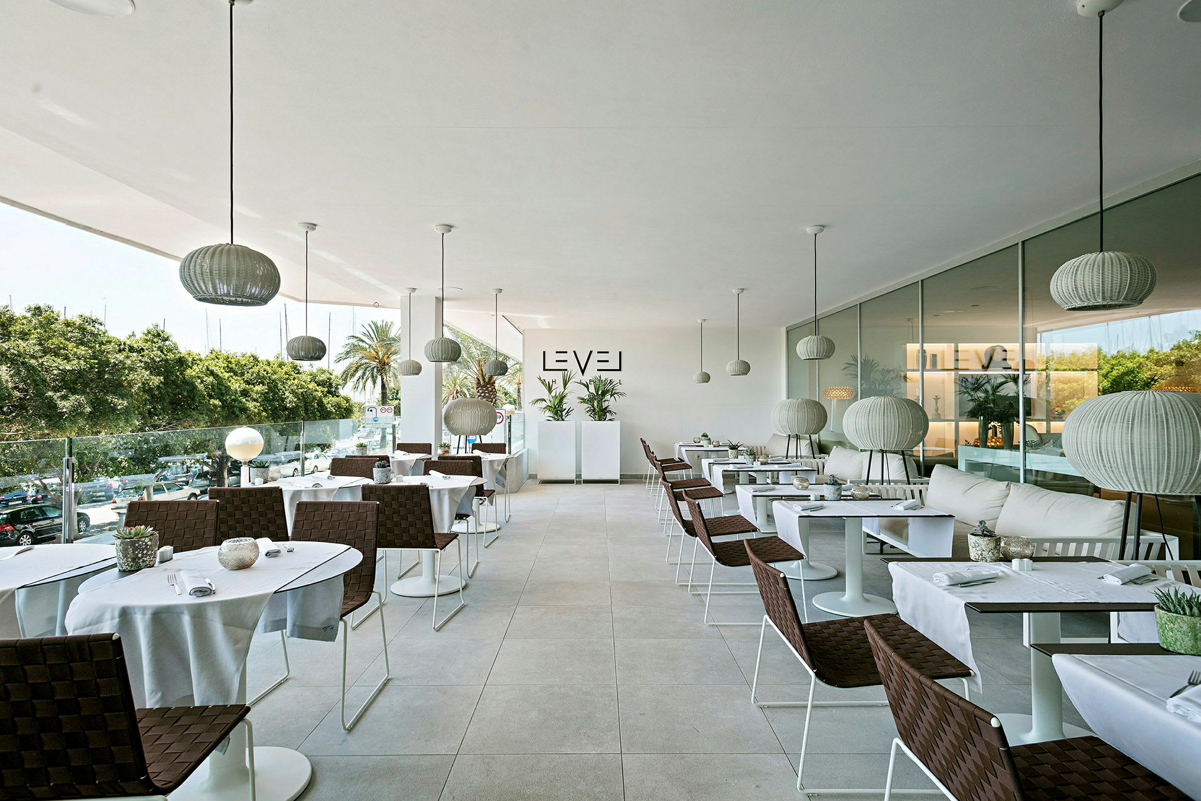 En modern restaurang med eleganta bord och stolar, stora glasfönster och ljushängande lampor. (AI-genererad text)