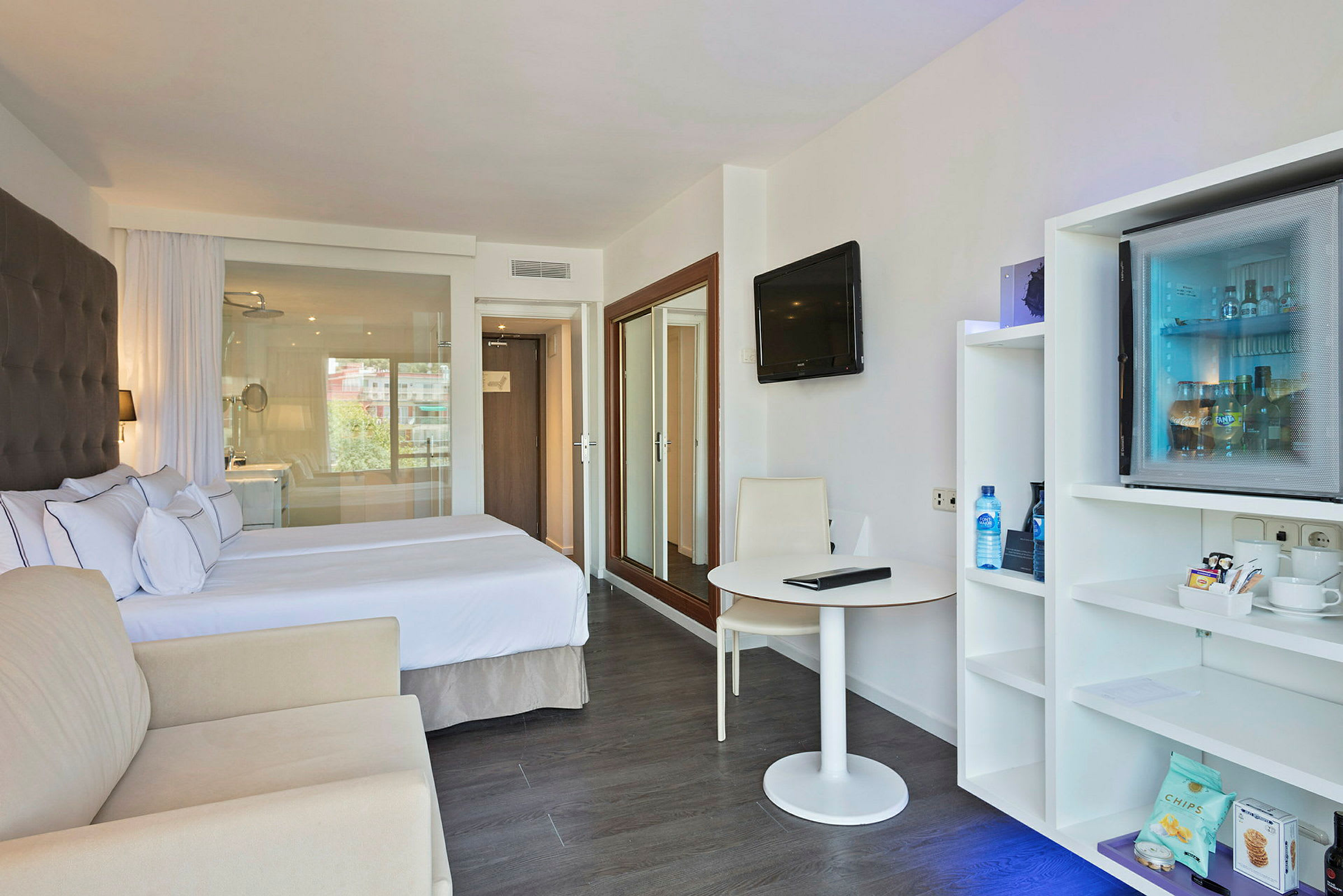 Hotellrum med dubbelsäng, sittmöbler, bord och en minibar. (AI-genererad text)