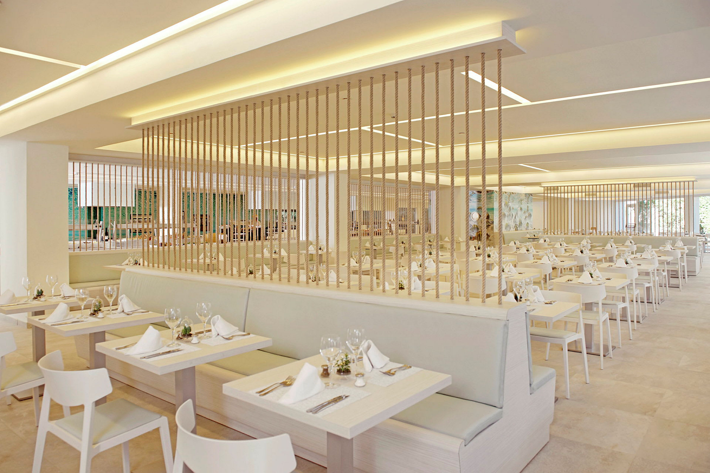 En modern och ljus restaurang med dukade bord i rad och dekorativa rep avgränsande delarna. (AI-genererad text)