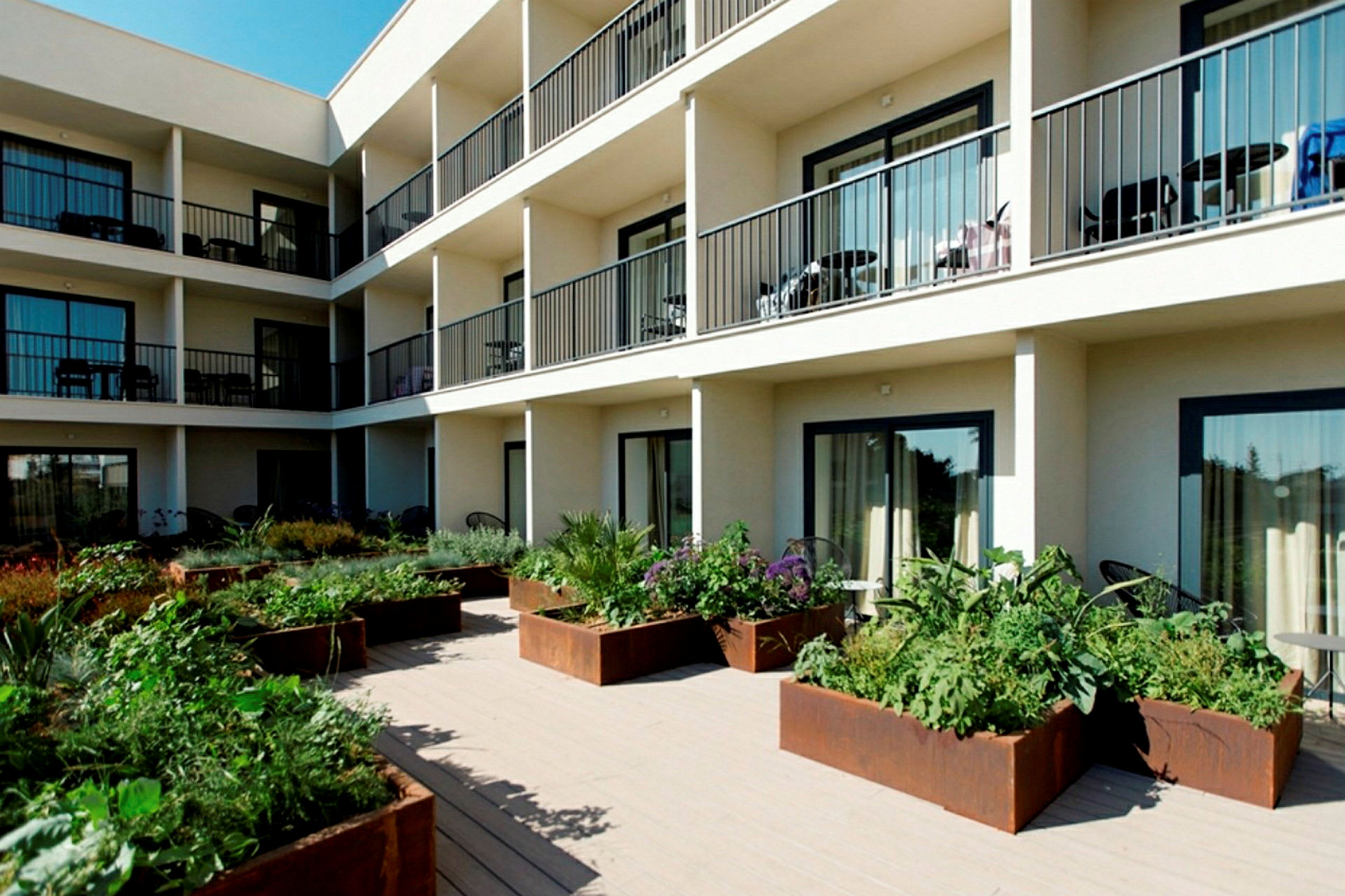 Modern byggnad med flera våningar, balkonger och en grönskande innergård. (AI-genererad text)